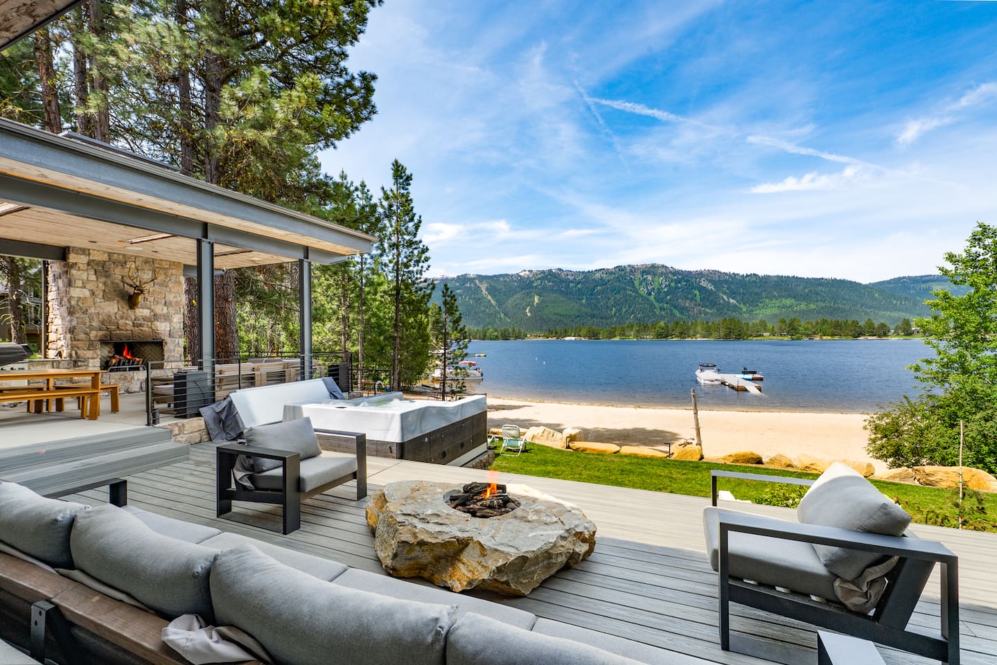 Relax in the hot tub while taking in panoramic lake and mountain views, all just outside the cozy stone fireplace patio
