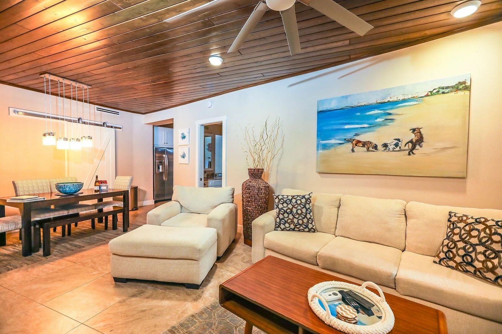 Cozy coastal living room with wood-paneled ceiling and local art.