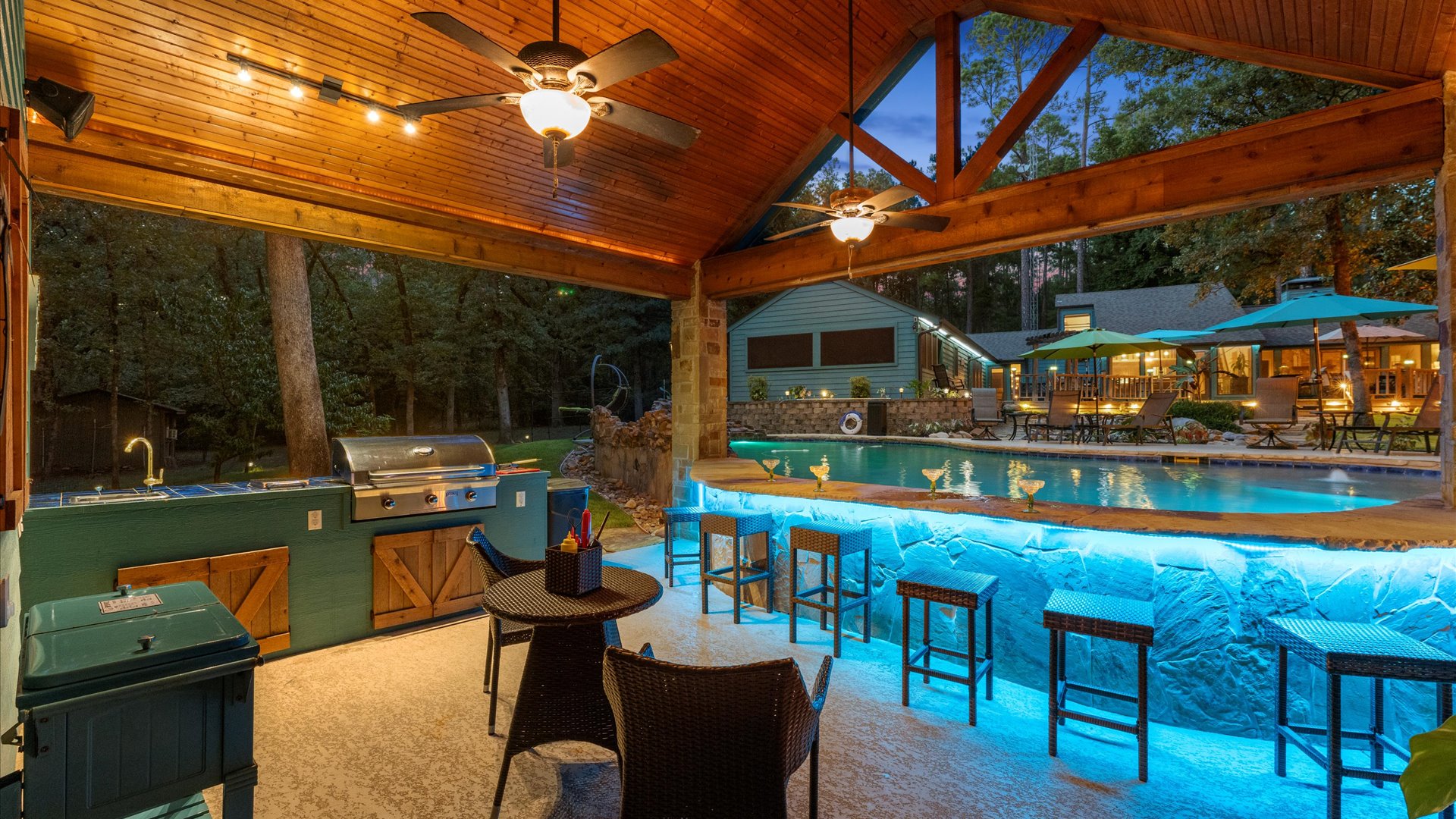 An entertainer’s paradise! This stunning outdoor kitchen and swim-up bar glow beautifully at night, offering the perfect spot to grill, sip drinks, and unwind by the pool in a serene, resort-like setting.