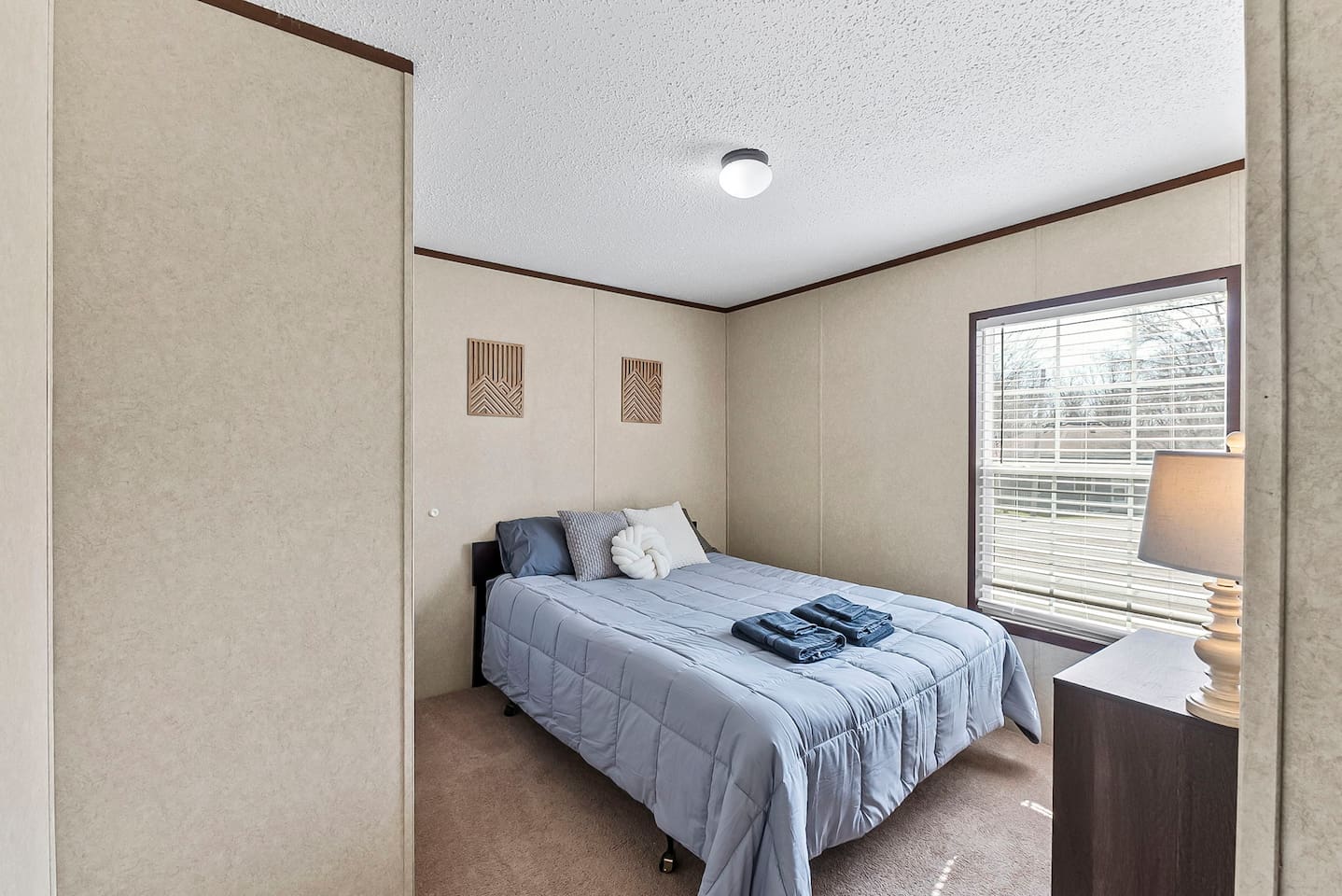 Cozy bedroom with a comfortable queen bed, soft natural light, and a large window creating a bright and relaxing space.