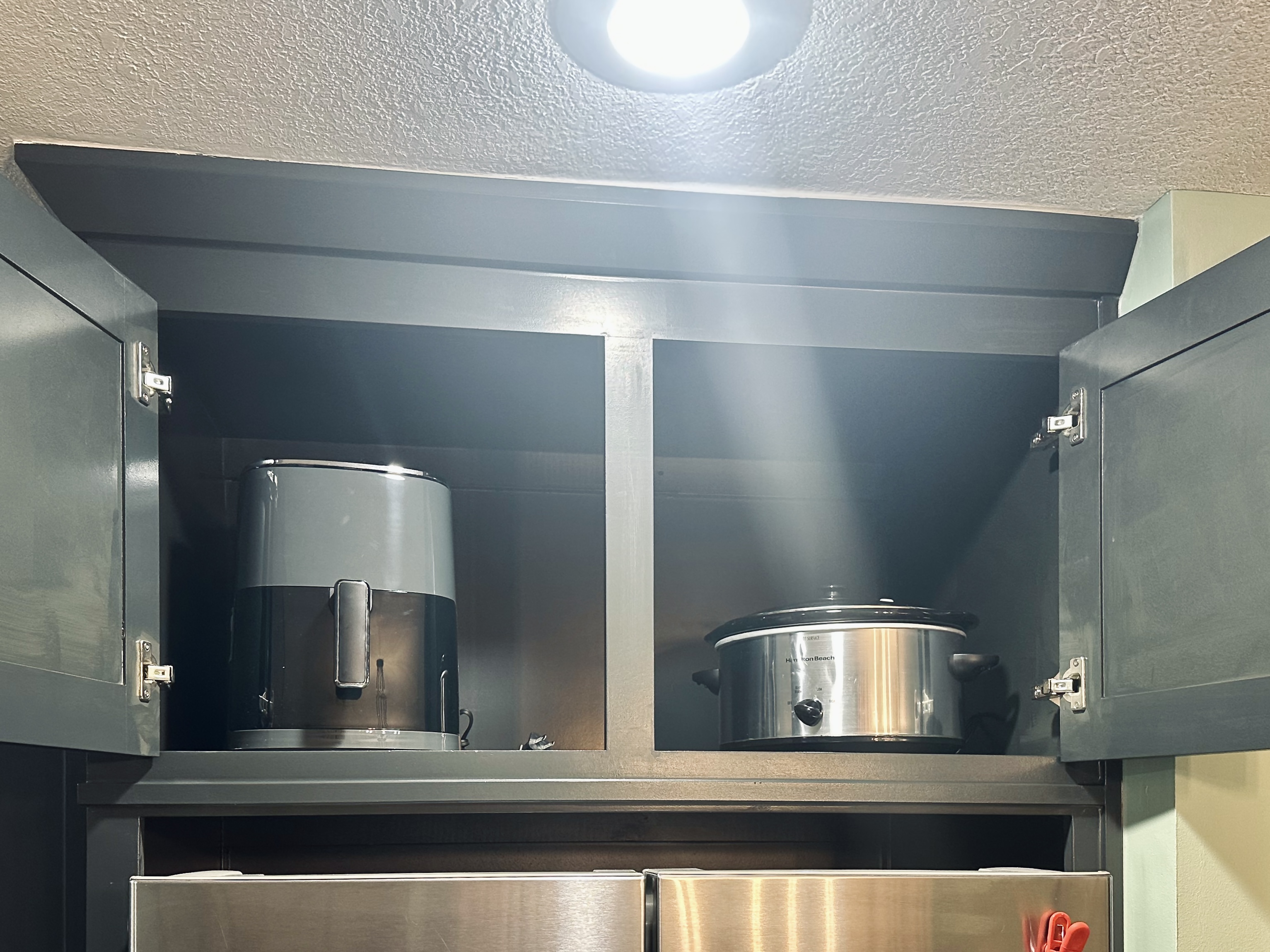 Kitchen cabinet featuring small appliances including an air fryer and crock pot to support easy, home-style meals.
