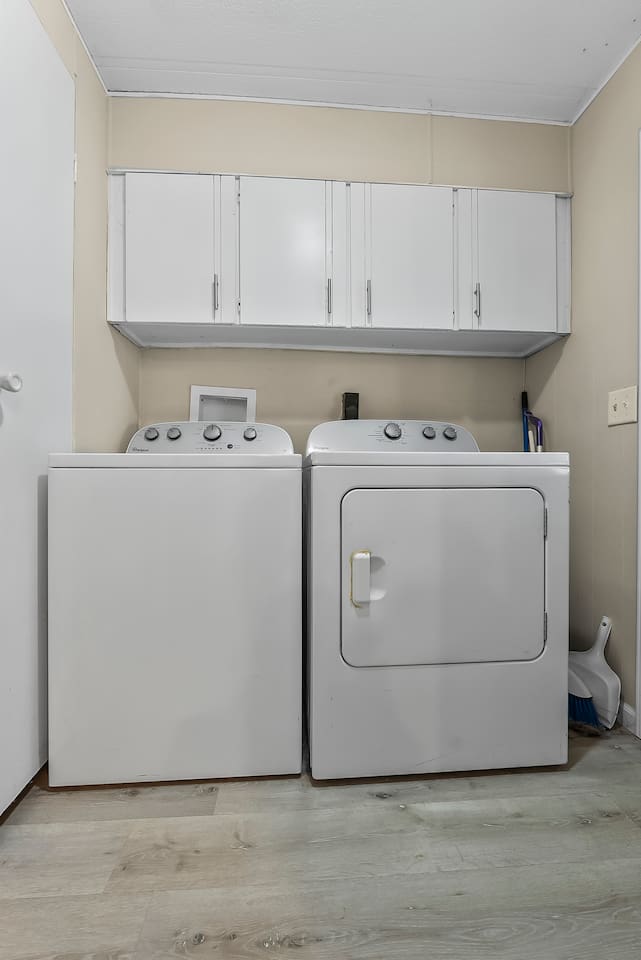 Laundry area with full-size washer and dryer, plus overhead cabinets for convenient storage.