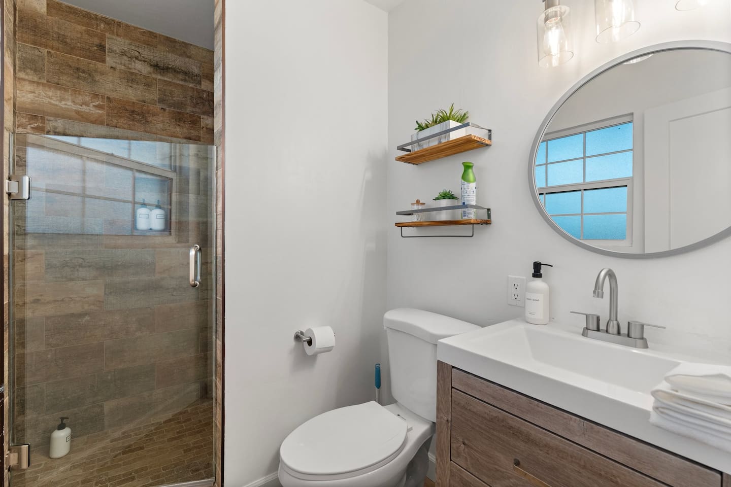 Clean and contemporary vanity area with open shelving, large mirror, and modern lighting makes getting ready a breeze.