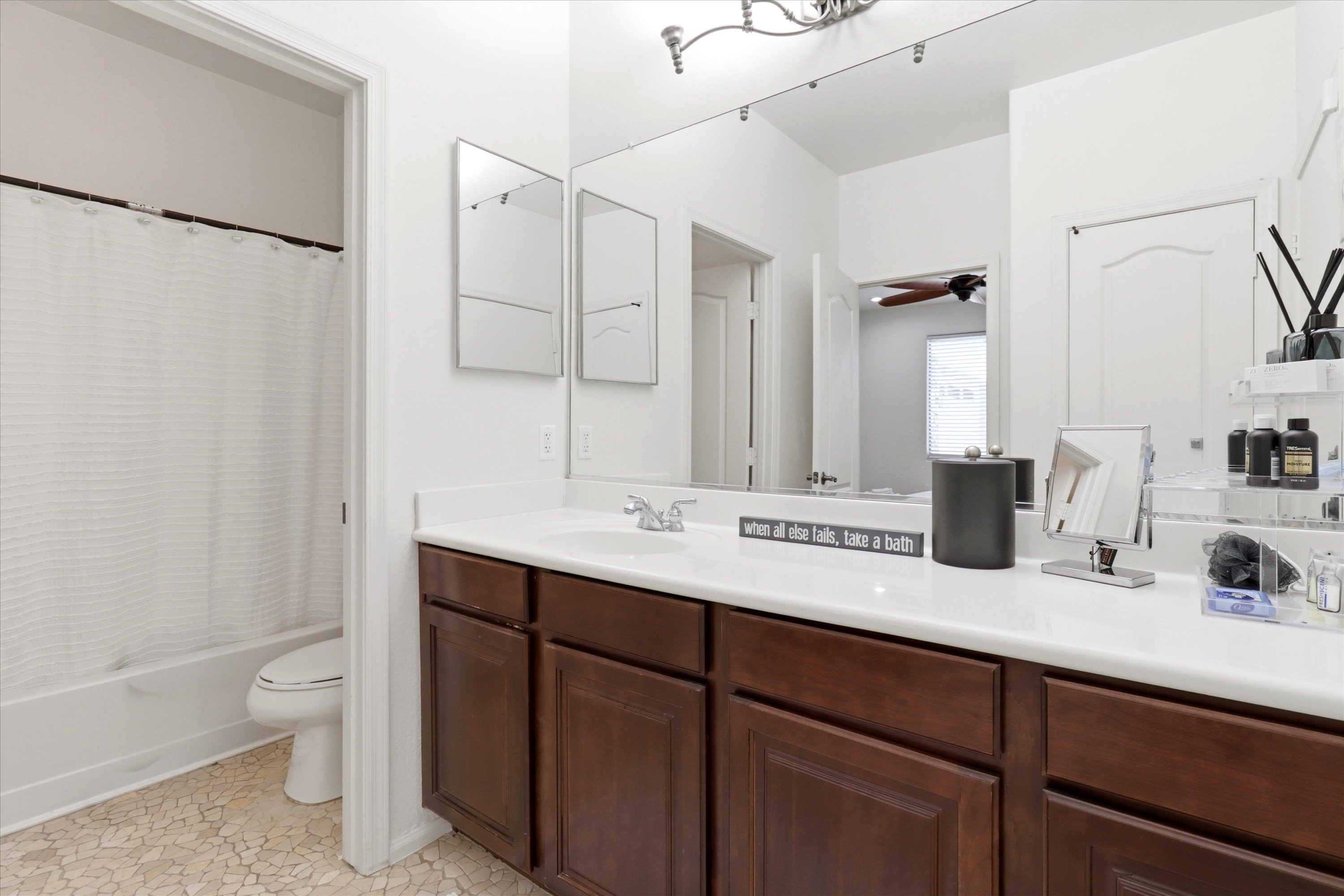 Bathroom vanity with lots of counter space, storage cabinets, and the shower area just off to the side.
