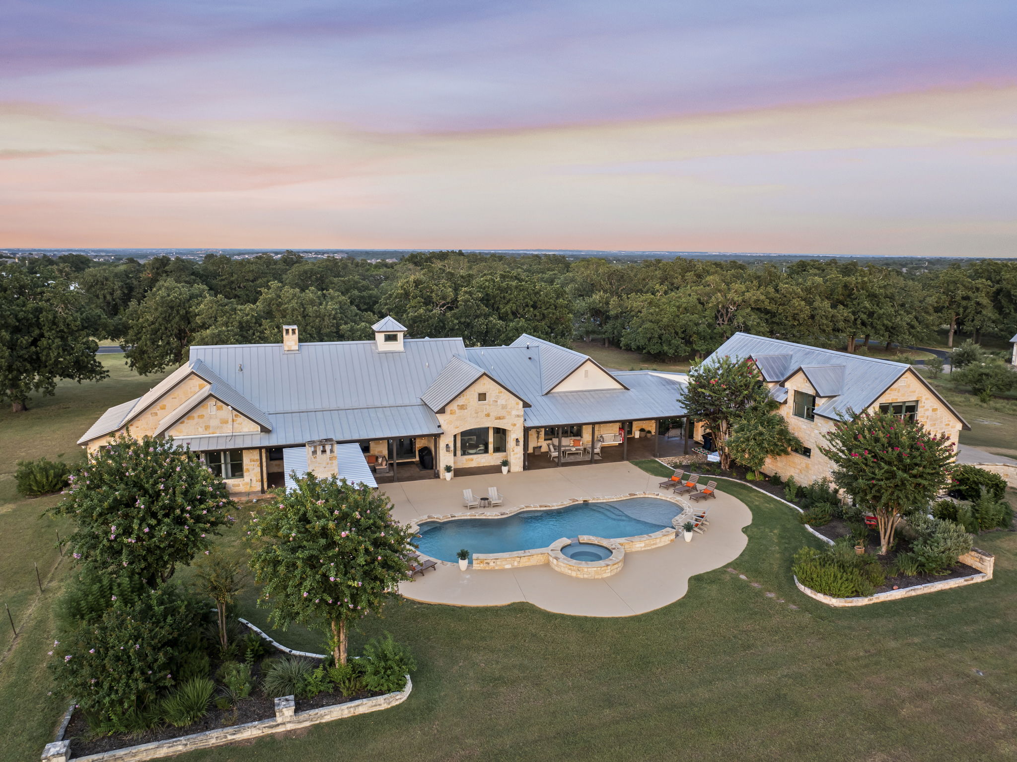 Bird's-eye perspective of a beautiful home and its expansive grounds, featuring a sparkling swimming pool and hot tub.