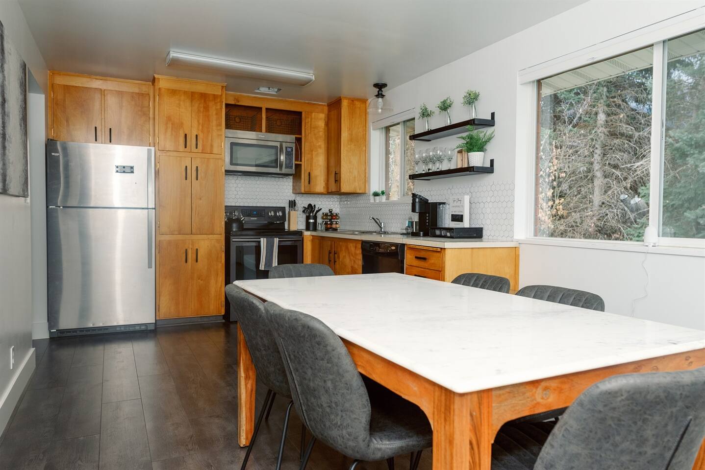 Another view of kitchen and dinning room, tons of light through large window showing the secluded backyard.