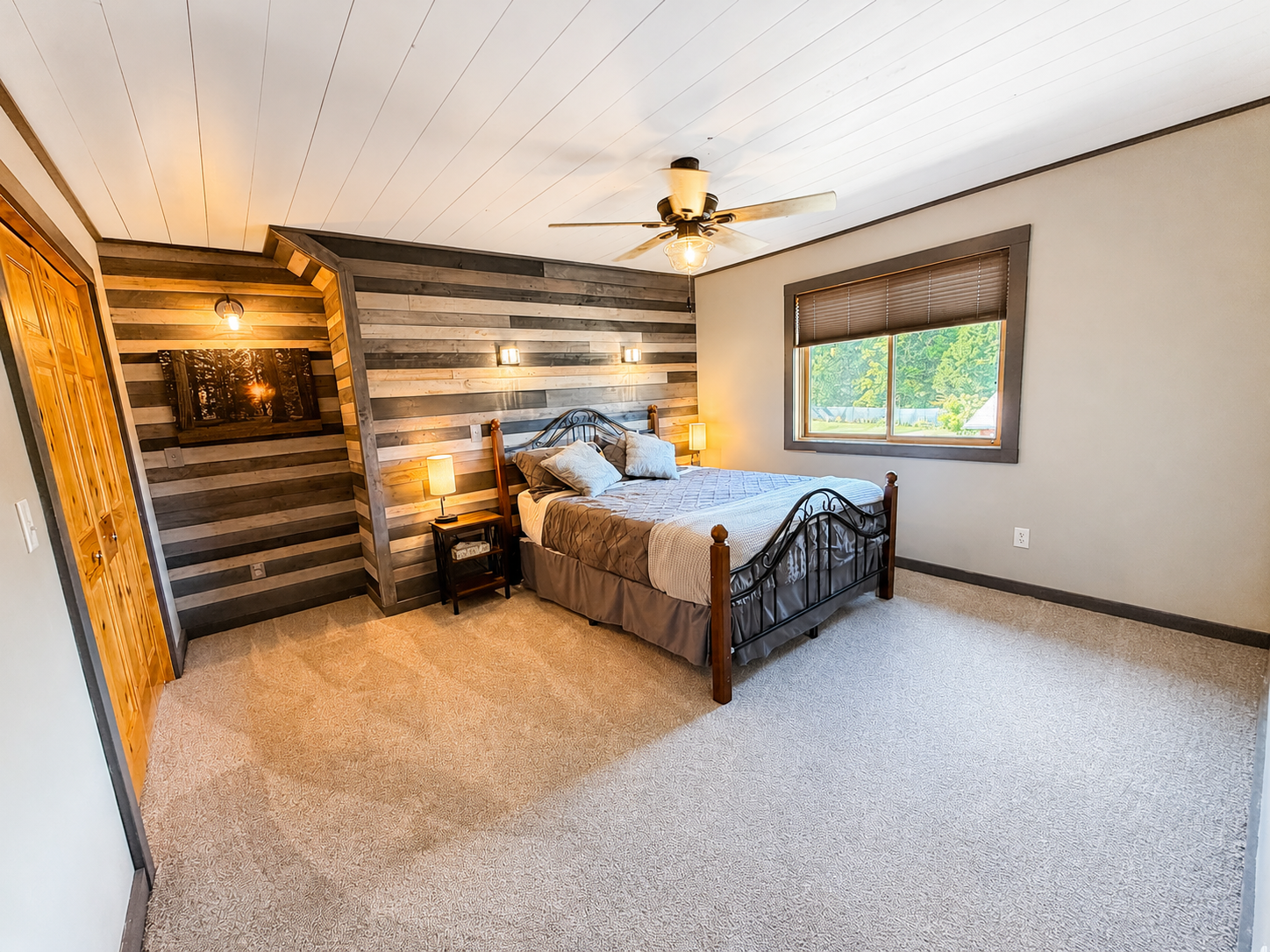 Comfortable guest bedroom with a rustic wood accent wall and plenty of space to recharge after a day on the trails.