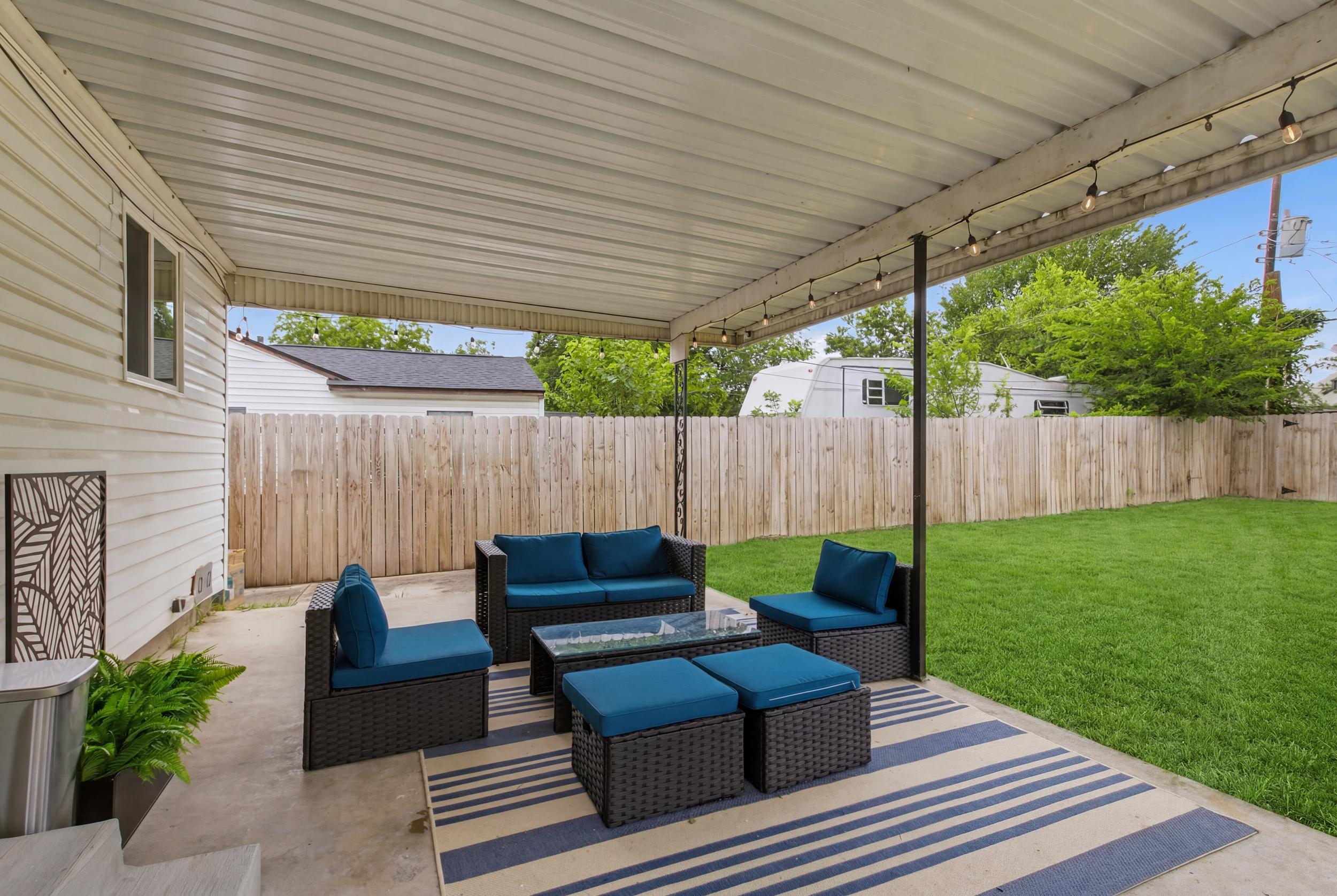 Covered Back Patio with Outdoor Furniture, Lounge Seating, and a view of the Fully Fenced Backyard. Shaded year-round comfort for groups of all sizes.
