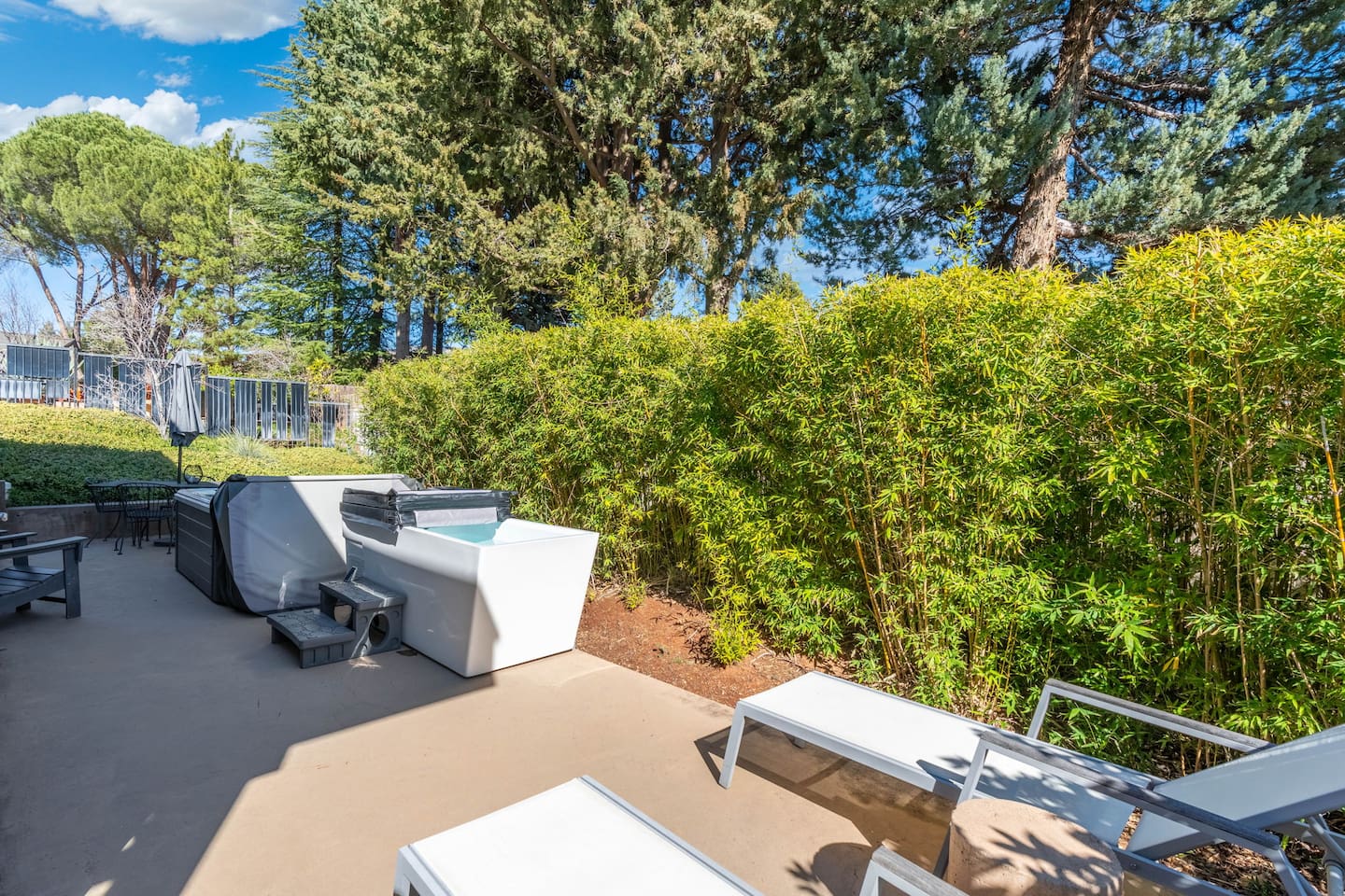 Secluded patio with hot tub, lounge chairs, and lush bamboo privacy for a peaceful outdoor escape.