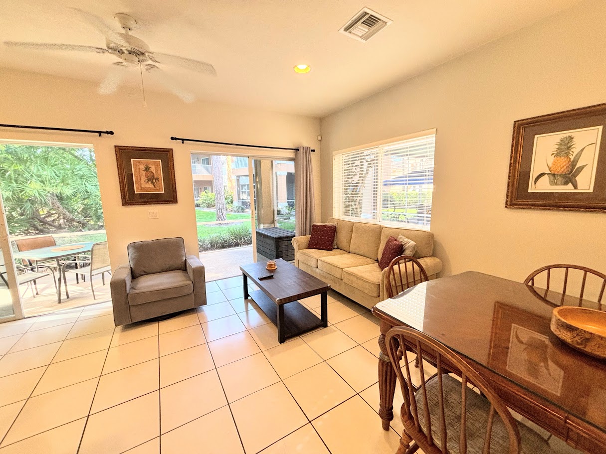 Spacious living and dining area with cozy seating, natural light, and sliding glass doors leading to the screened patio.