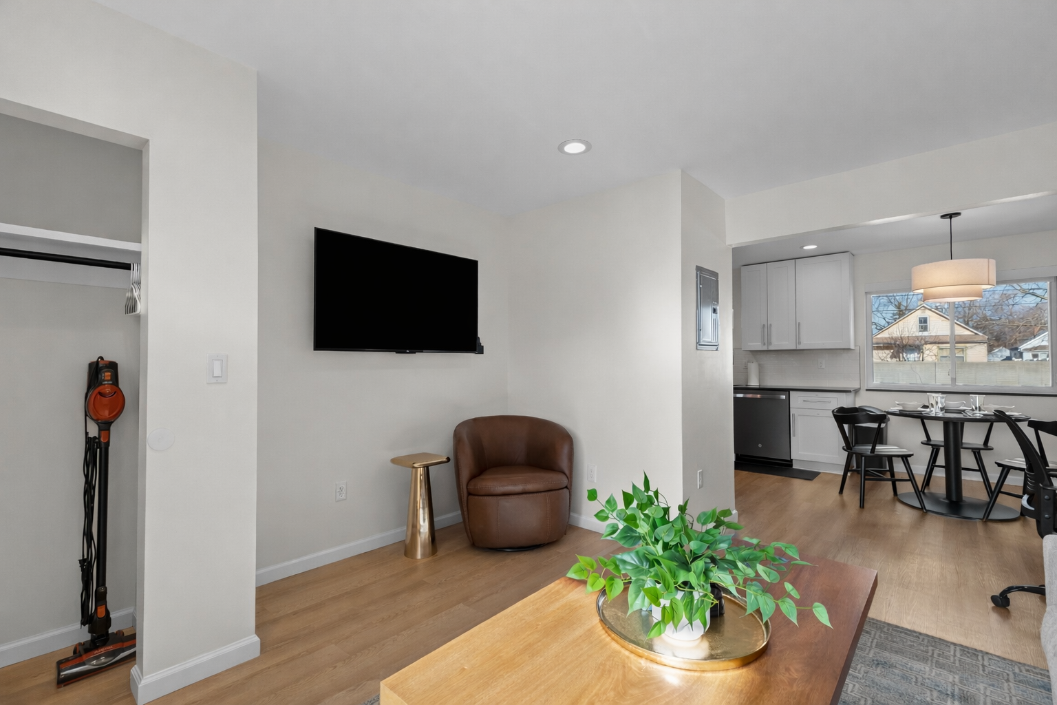 Relax in this bright living area featuring a comfy lounge chair, smart TV, and open flow to the kitchen and dining space—perfect for unwinding or entertaining.