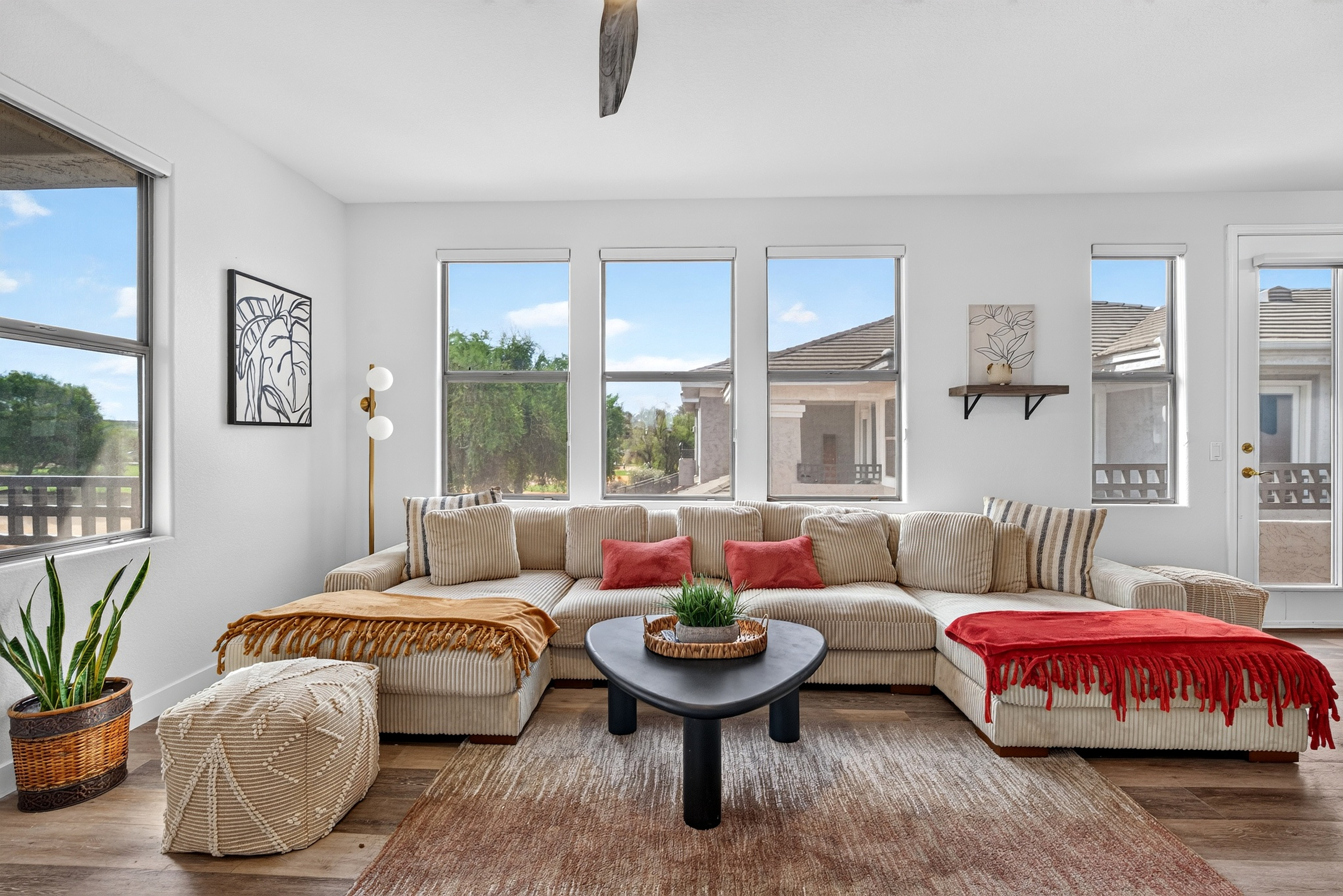 Living room with oversized sectional seating, wide windows, and open views of the desert landscaping outside.
