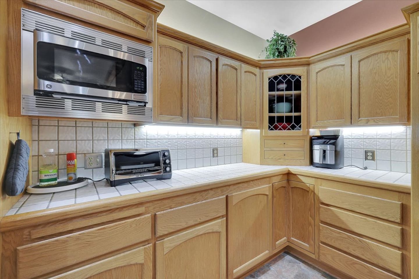 Kitchen counter area with microwave, toaster oven, coffee maker, and cabinet storage.
