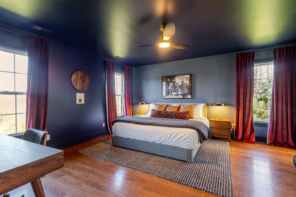 Rich navy walls, warm leather accents, and a touch of vintage charm — this upstairs king bedroom captures Kentucky’s timeless elegance, offering a restful retreat steeped in quiet character.