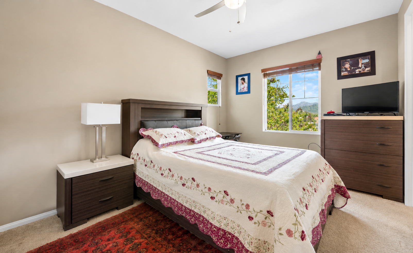 Bedroom with a comfortable bed, dresser storage, TV, and sunny window views.