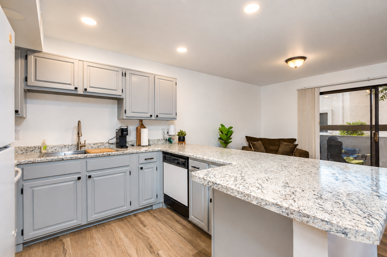 Kitchen with gray cabinets, full appliances, and a wide counter for meals or serving.
