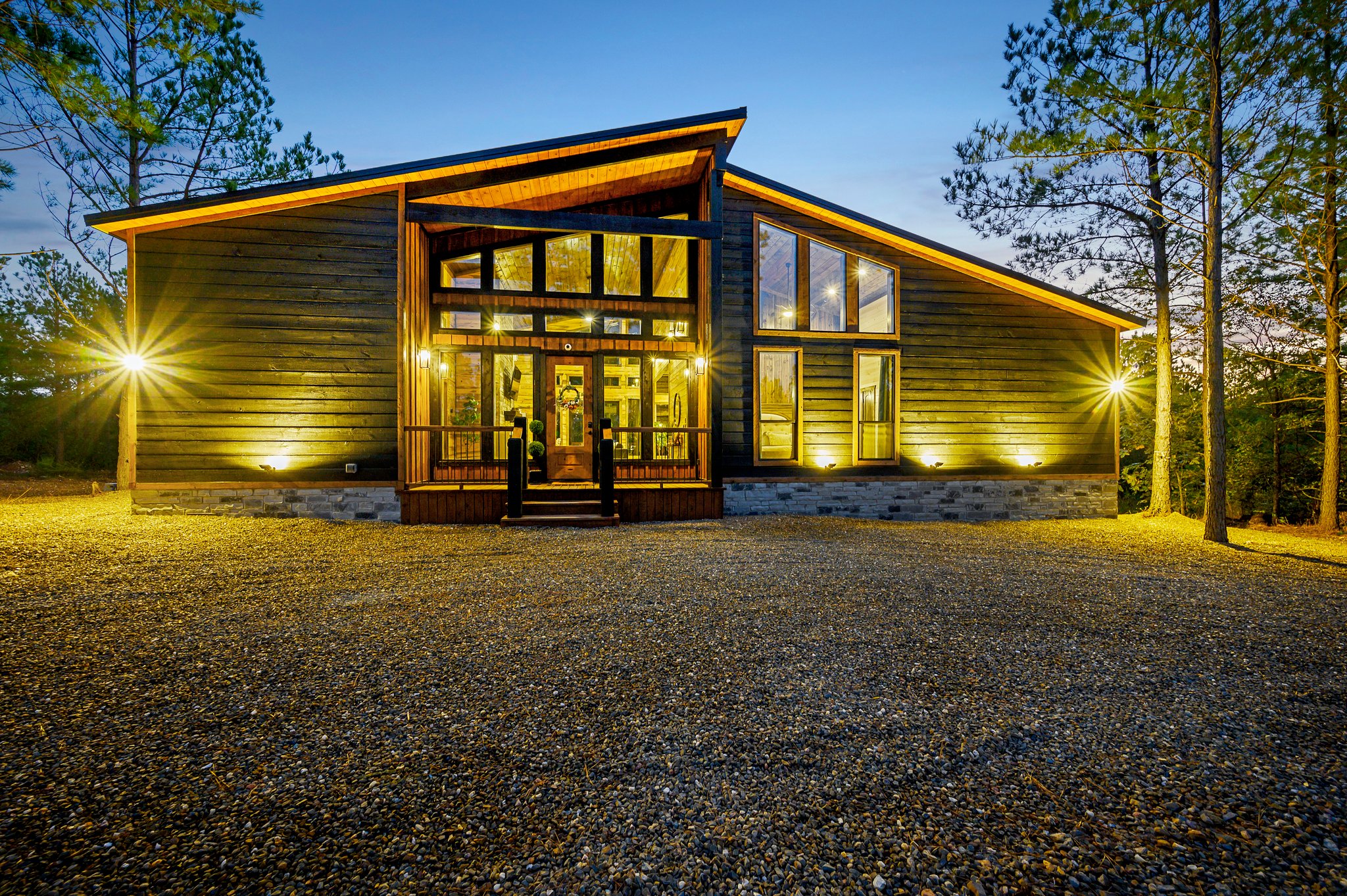 A stunning modern cabin retreat nestled among towering pines, glowing warmly at sunset.