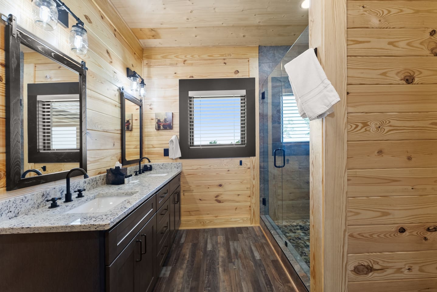 Bright and modern full bathroom with large window views and a glass walk-in shower—comfort meets cabin charm.