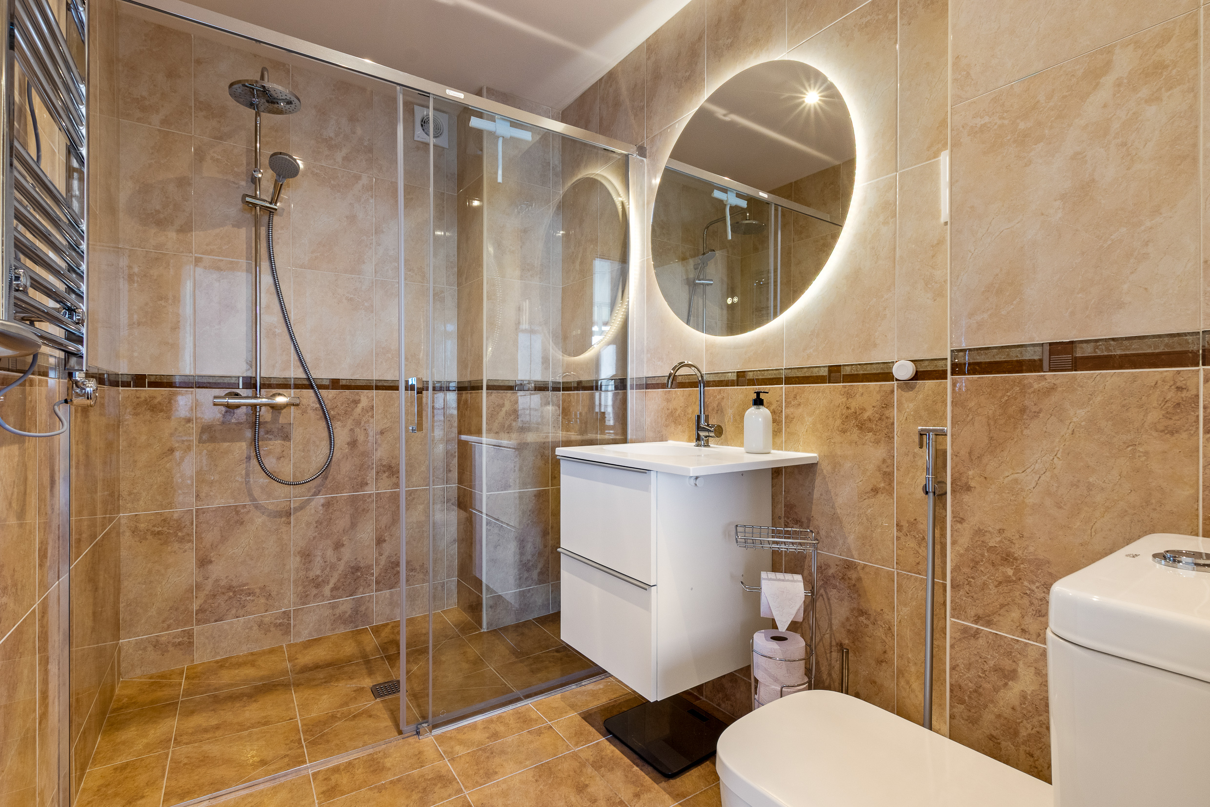 Bathroom with walk-in shower, rainfall showerhead and illuminated mirror.