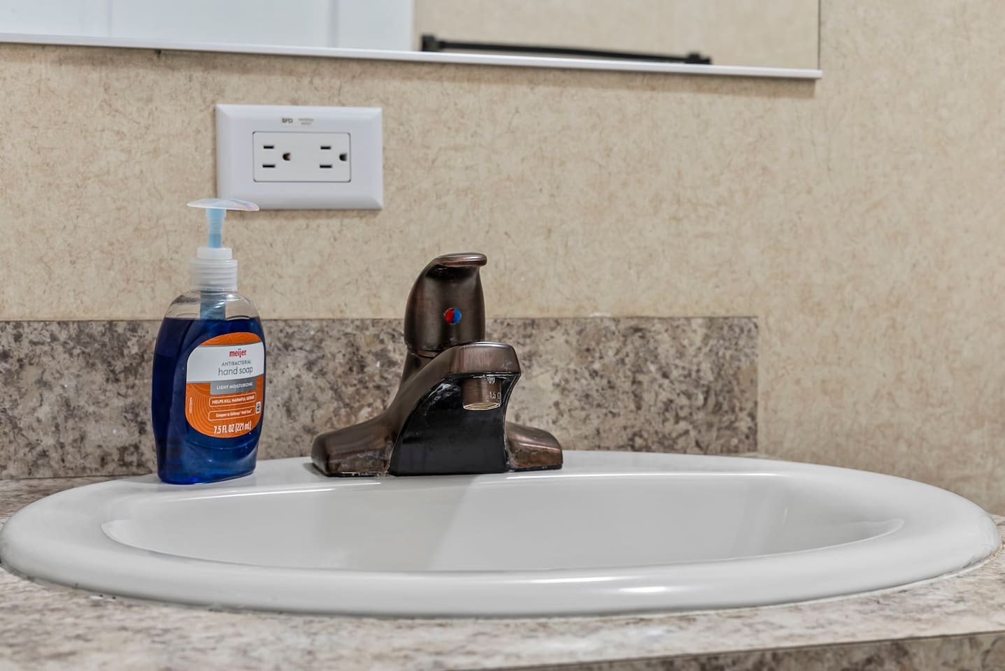 Close-up of the sink area featuring modern fixtures, clean countertops, and essential toiletries for guest convenience.