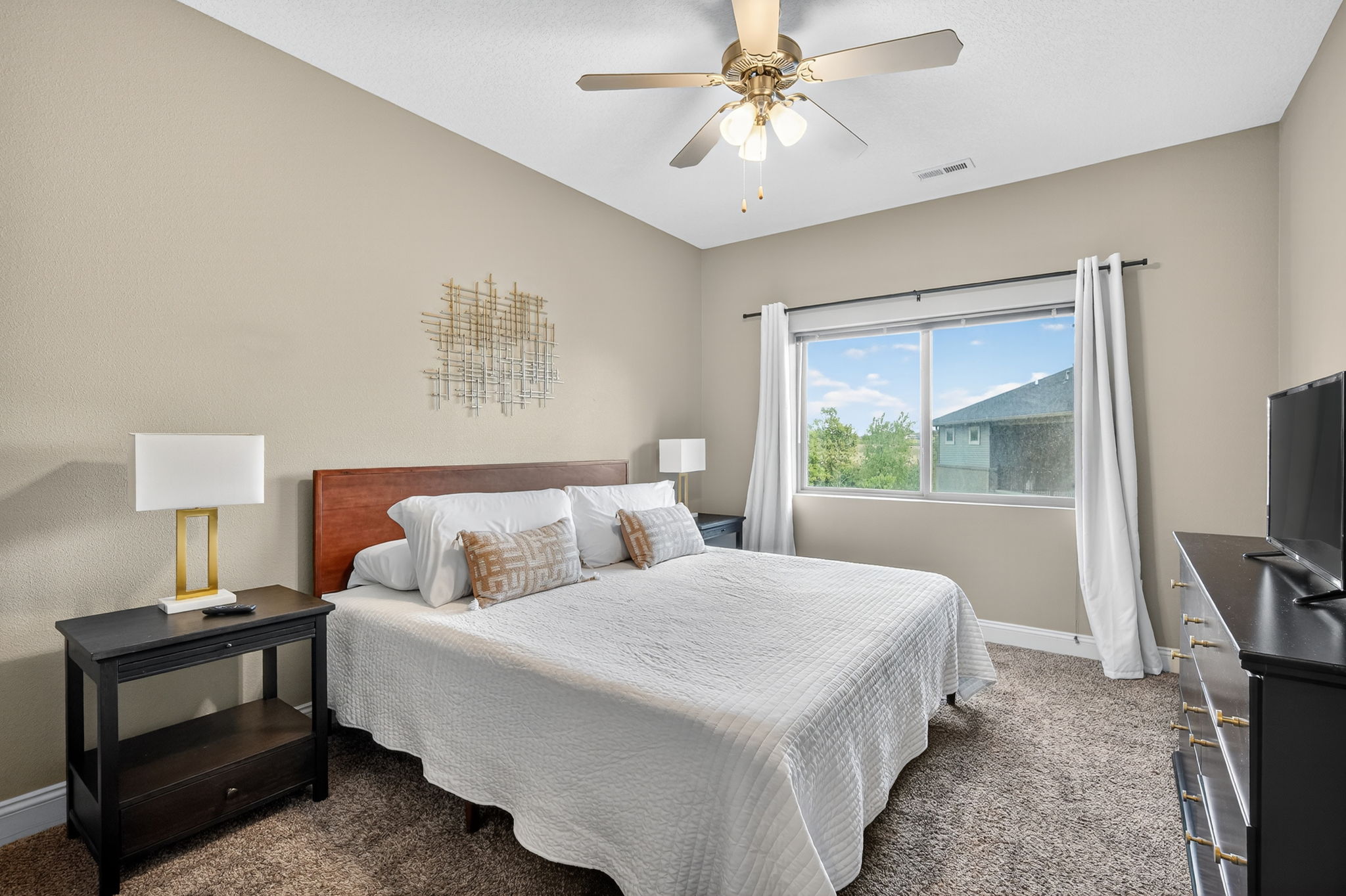 Unwind in the spacious king bedroom with crisp white bedding, modern lamps, and large windows. Wake up refreshed with views of treetops and natural light streaming in, setting the tone for a s