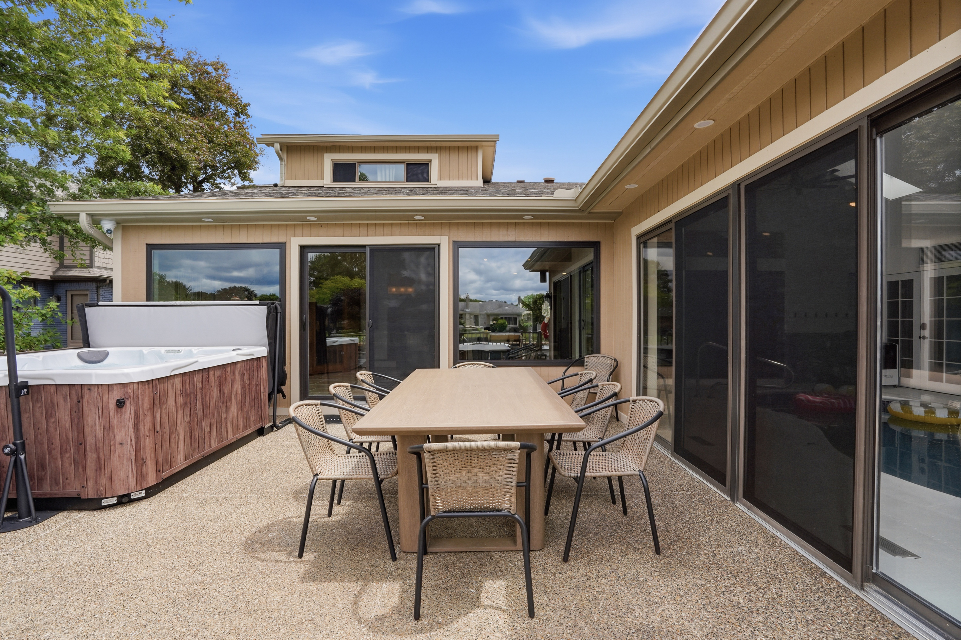 Spacious outdoor patio with dining table, seating, and a private hot tub. Perfect for relaxing, entertaining, and enjoying warm-weather lake house living.