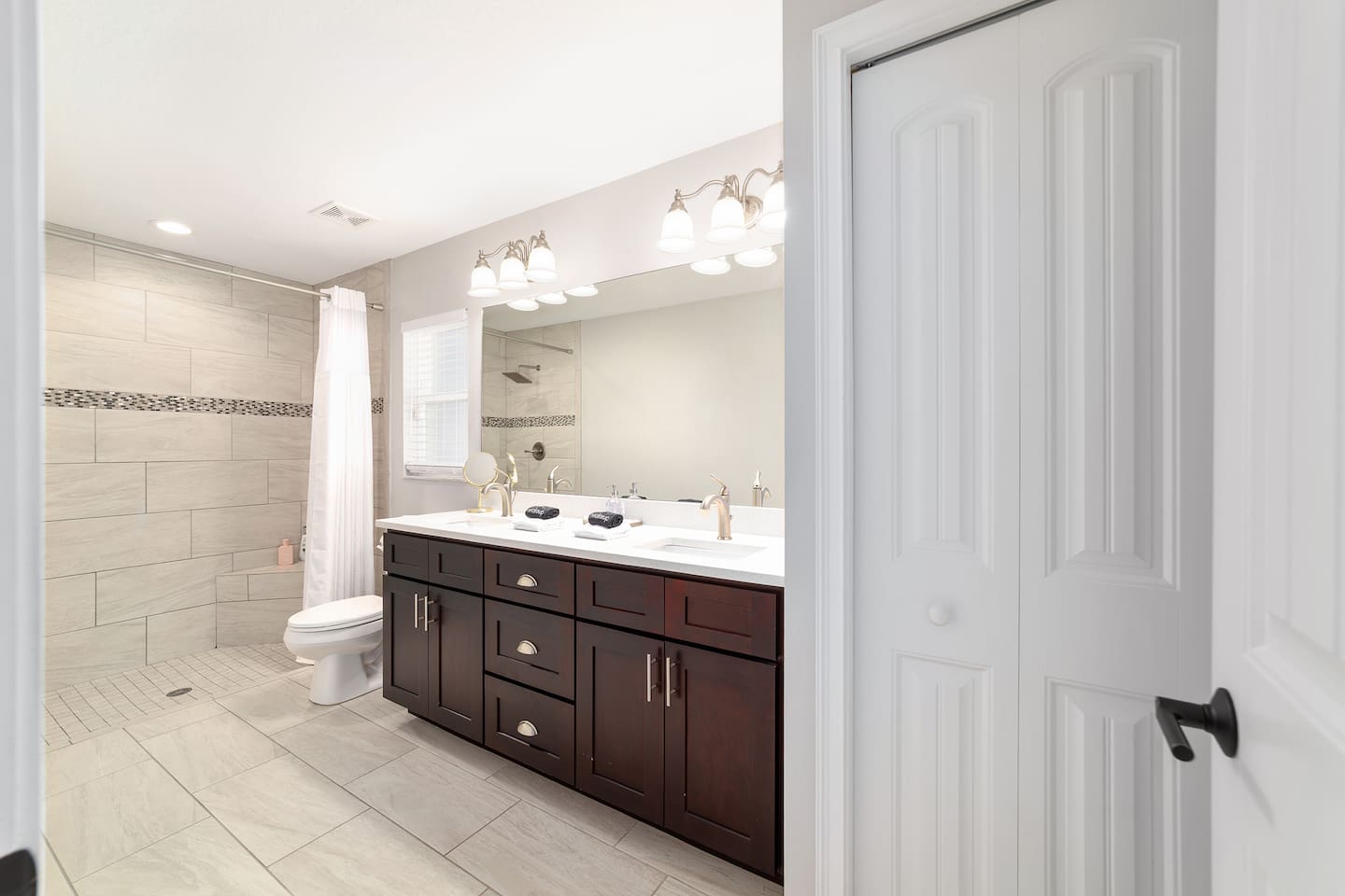 Enjoy a beautiful  en-suite featuring a large walk-in shower, a double-sink vanity with plenty of counter space, bright lighting, and thoughtful touches throughout. This fresh, spa-like bathroom offers comfort and convenience for a relaxing stay.