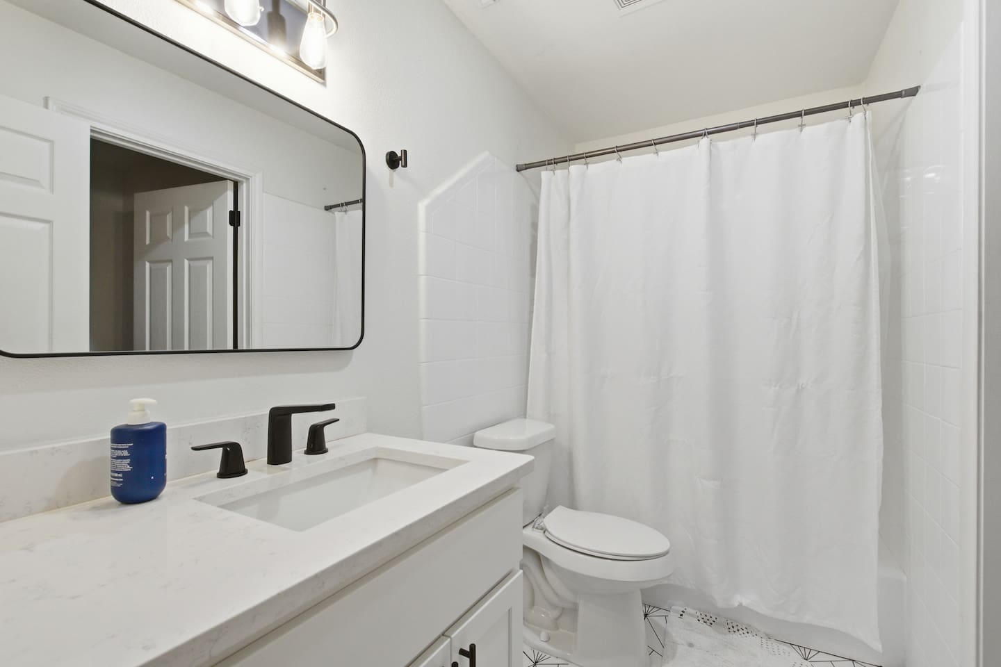Bright full bathroom with bathtub and shower combo, modern vanity, fresh towels, and clean hotel-style finishes.