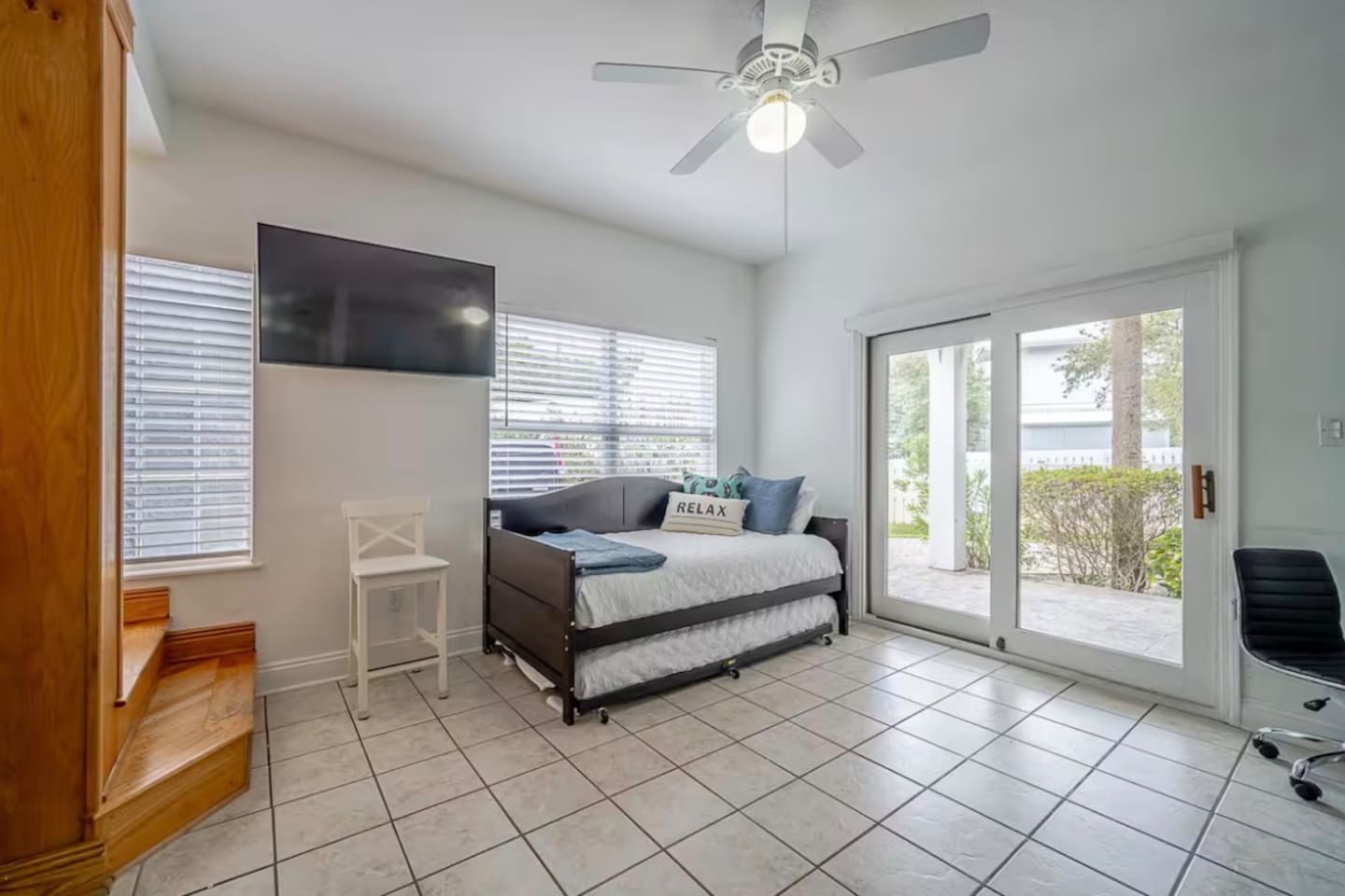 Versatile daybed with trundle setup in the bunk room, providing comfortable extra bedding and a wall-mounted TV for entertainment