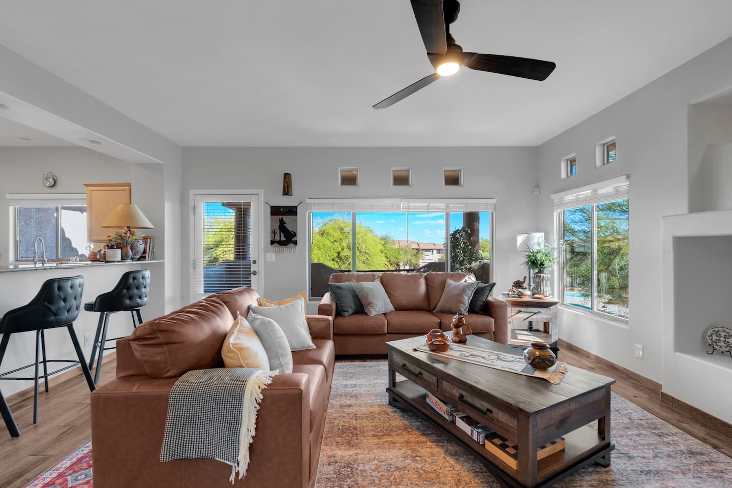 Spacious living room with leather sofas, coffee table, balcony access, barstools