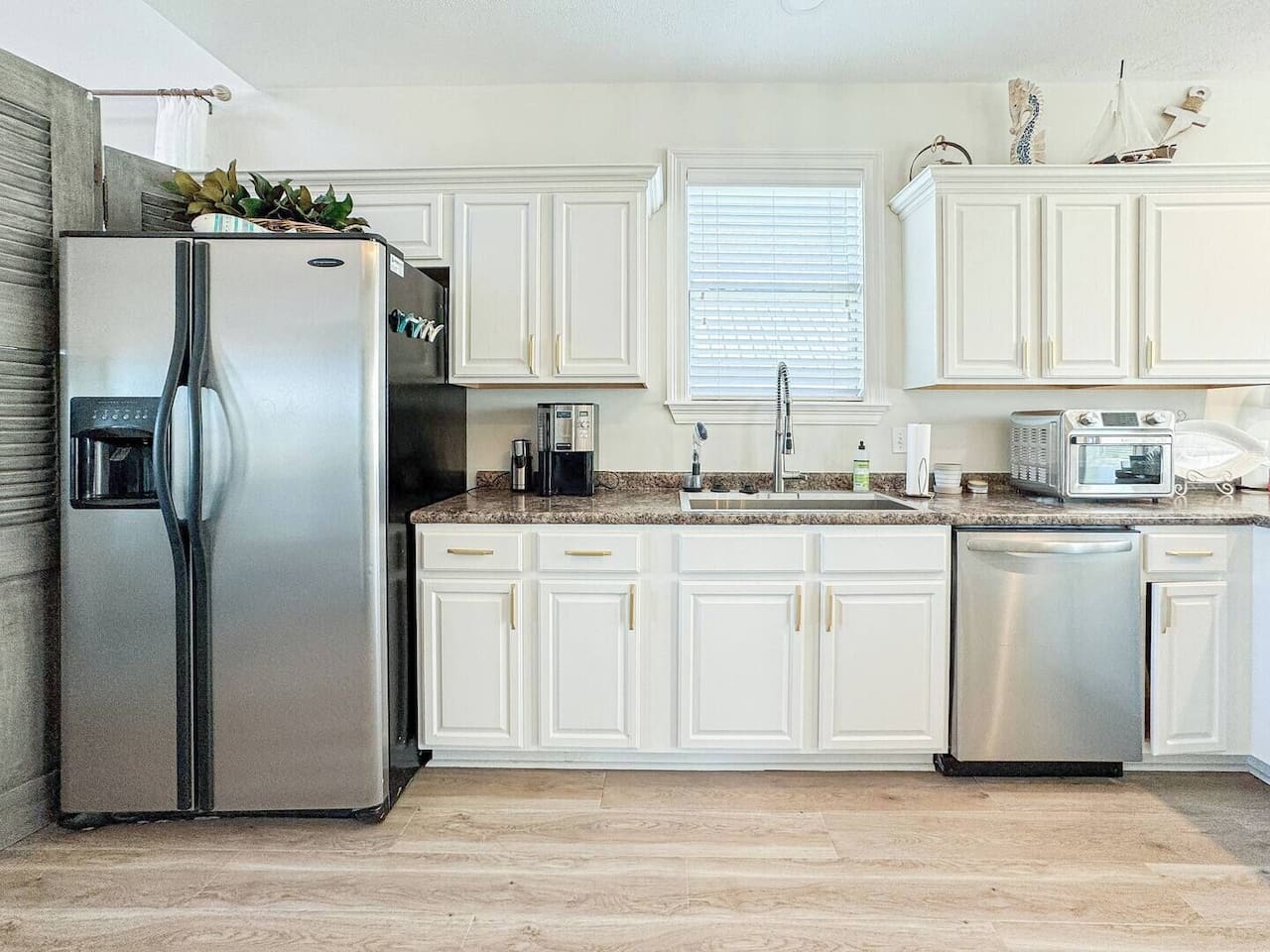 Spacious, sunlit kitchen featuring ample counter space, stainless steel appliances, and stylish lighting, perfect for cooking.