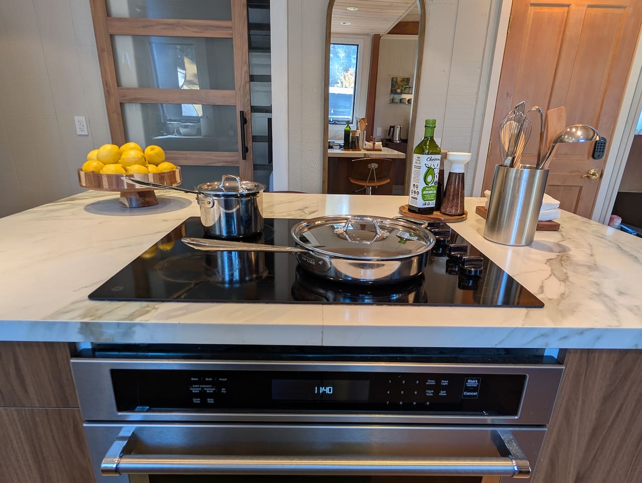Cook like a pro in this gourmet kitchen, fully equipped with a modern induction cooktop, premium All-Clad stainless steel cookware, and plenty of marble counter space for meal prep.