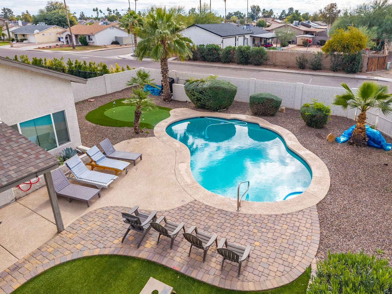 Resort-style backyard with sparkling pool, spa, putting green, and multiple lounging areas.