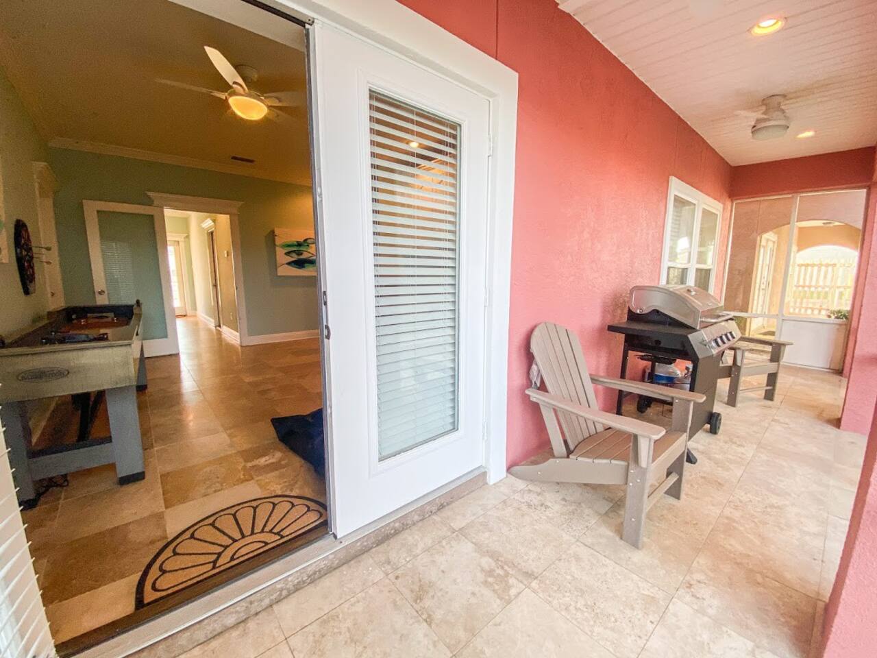 Screened in back porch with Adirondack chairs and propane grill and view into the first floor sitting area.  If you turned around from this spot you would see the pool and lake.