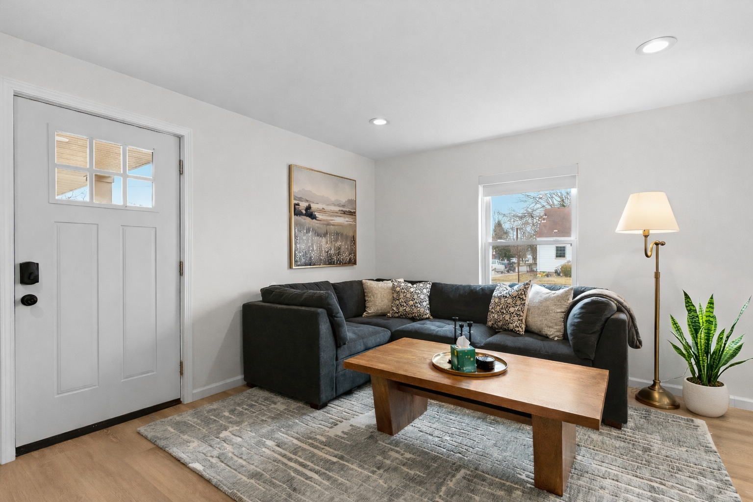 Unwind in this cozy living area featuring a plush sectional, warm wood accents, soft lighting, and natural light that creates a calm, inviting retreat.