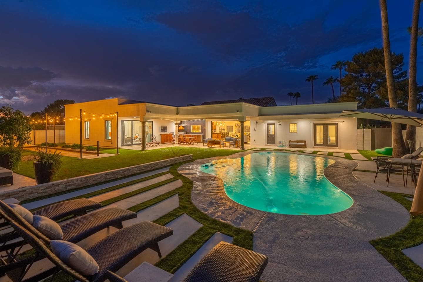 Discover the charm of nighttime by the pool, with trees aglow in soft patio lights. Lounge comfortably and create unforgettable memories under the dim night sky!
