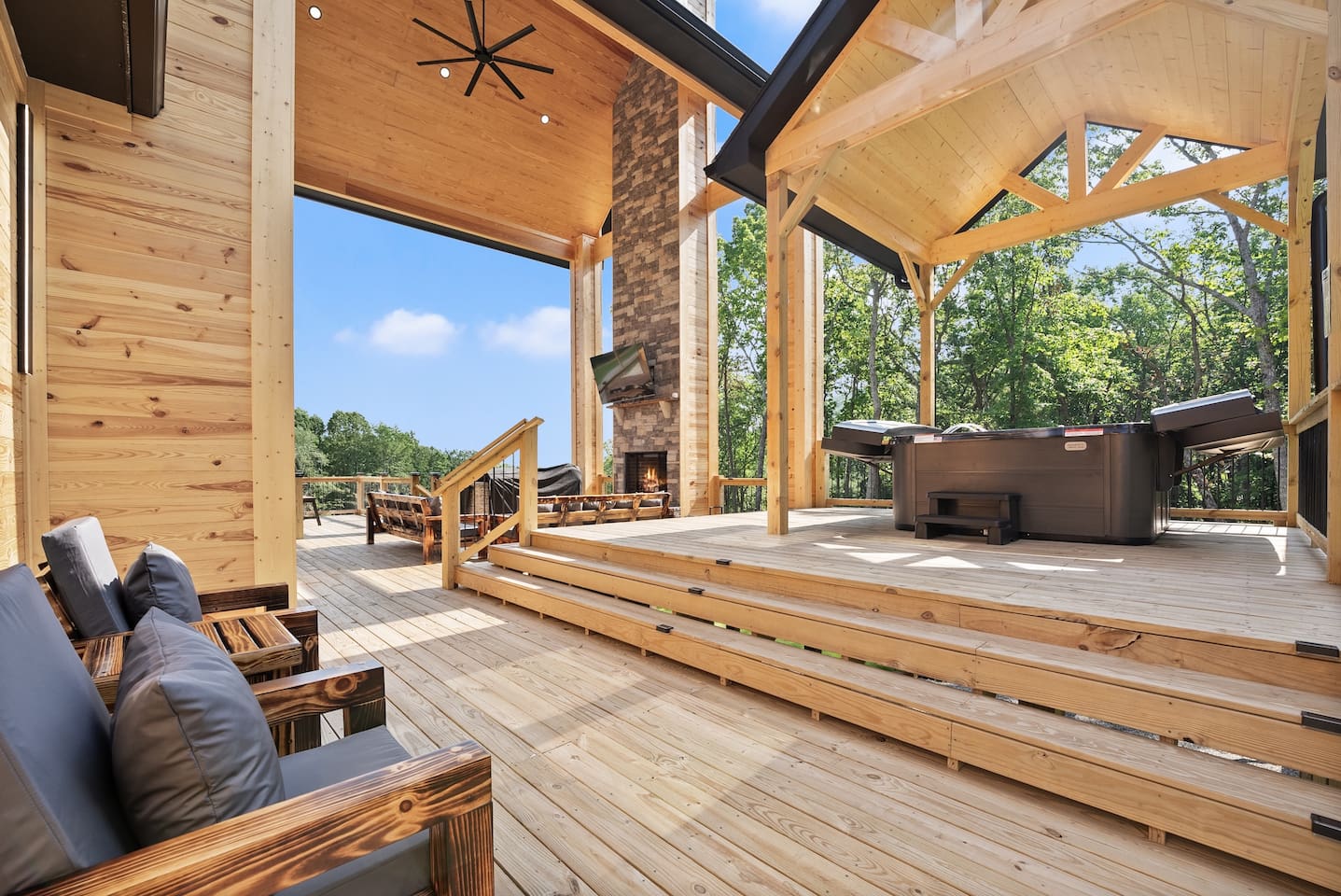 The elevated patio design highlights beautiful craftsmanship and leads to a private hot tub under a vaulted wood pergola, perfect for day or night relaxation.