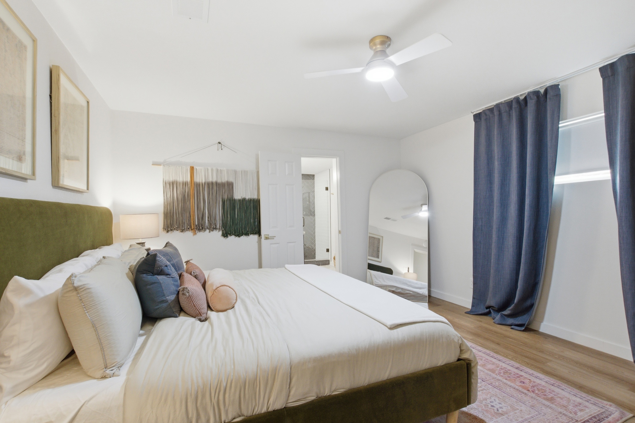 King Bed guest suite with ceiling fan, arched mirror, and room-darkening curtains. Lock on bedroom door and clothing storage included.