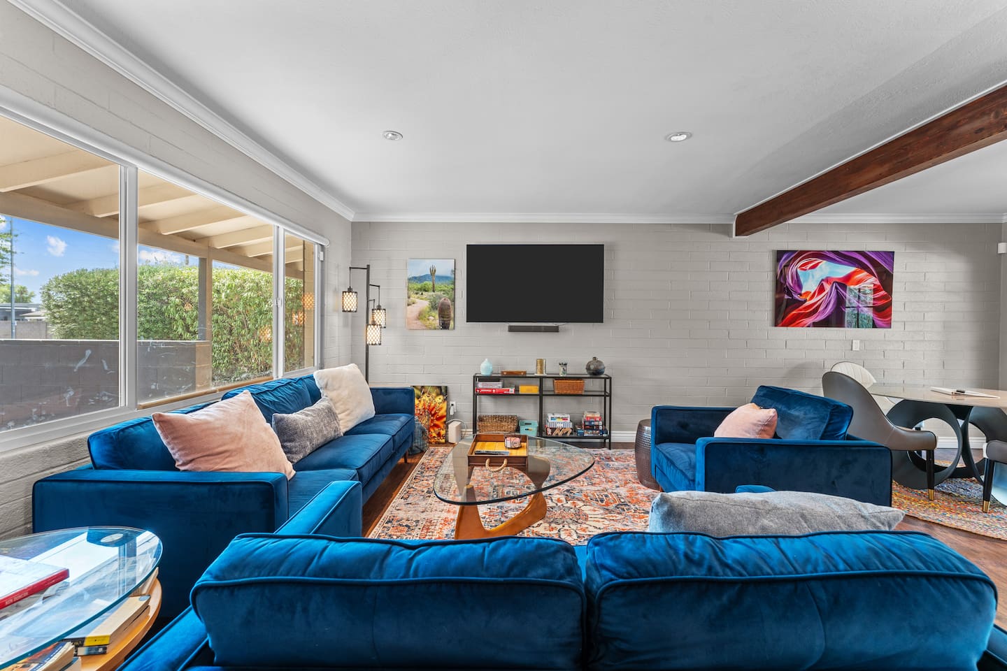 Spacious living room with velvet seating, large smart TV, and backyard views.