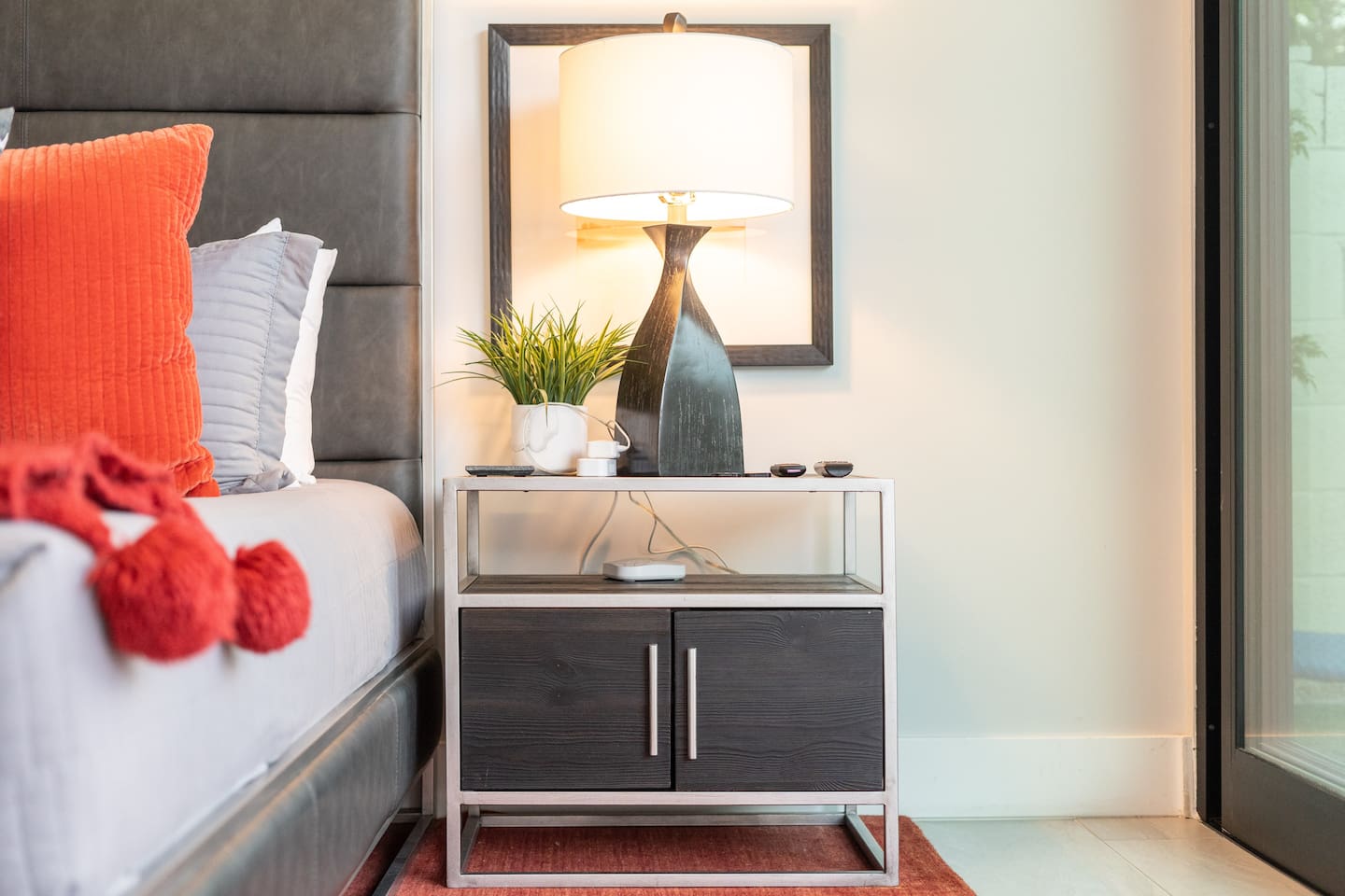 The right-side nightstand balances lighting and greenery, offering a calming bedside experience with thoughtful accessories.

