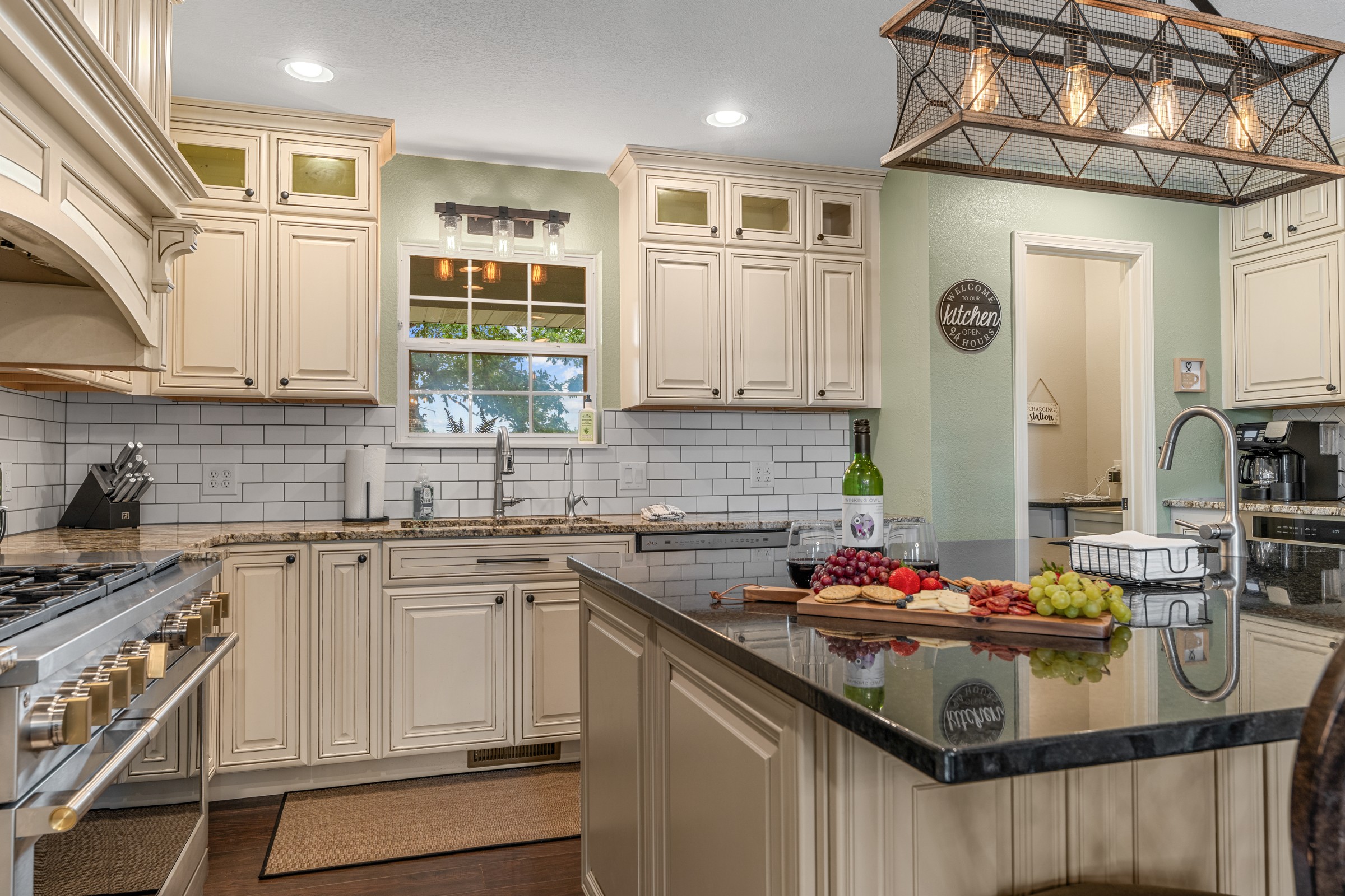Kitchen with granite island, wine and a charcuterie board. A range at the left and plenty of counter space make gathering easy.
