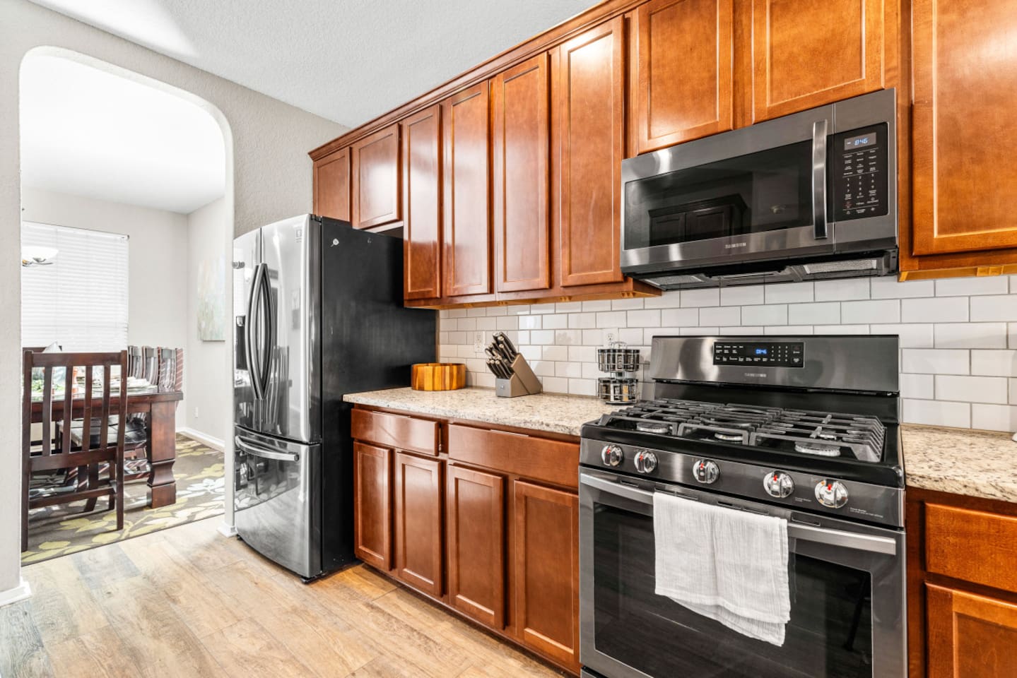 Spacious kitchen with full fridge/freezer combo, stainless steel oven, microwave, gas cooktop, and all cooking tools, pots, pans, dishes, and cutlery included.