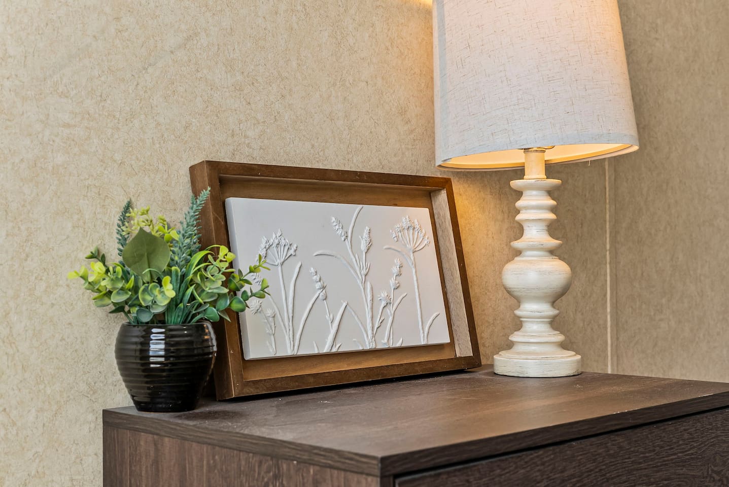 Charming bedside setup with a lamp, greenery, and elegant décor for a cozy, home-like feel.