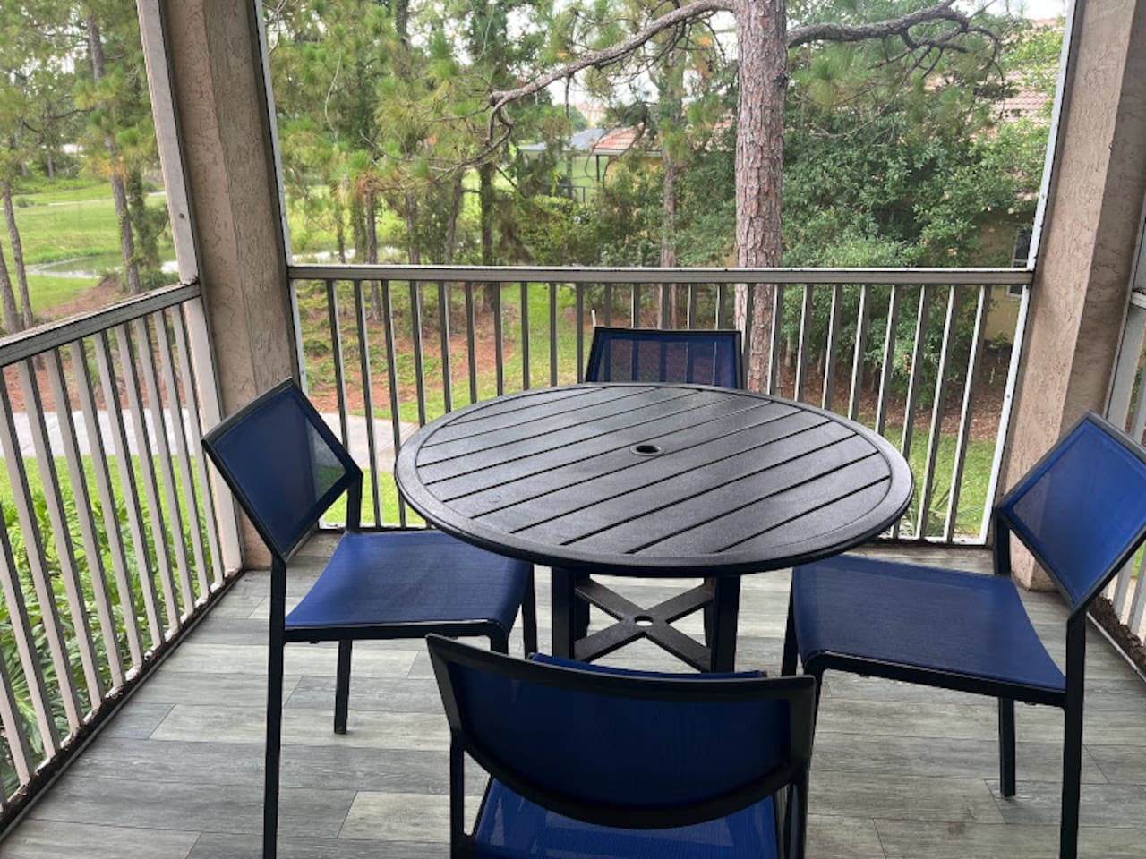 Private screened balcony with outdoor seating and peaceful views of the surrounding greenery.