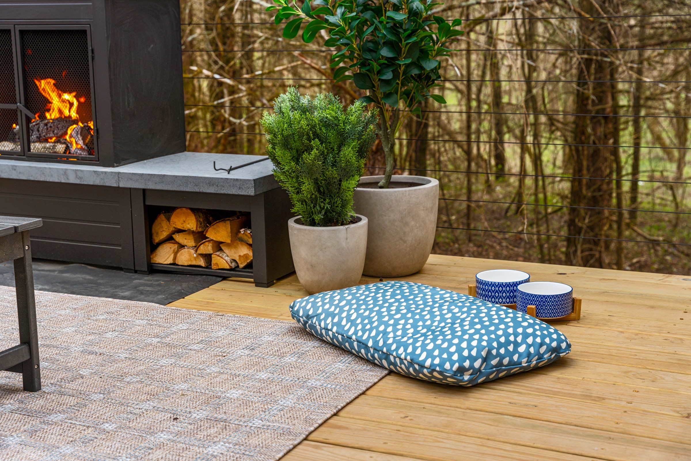 Dog bed and bowls on the deck by the outdoor fireplace. Your pups are welcome and have their own spot by the fire!
