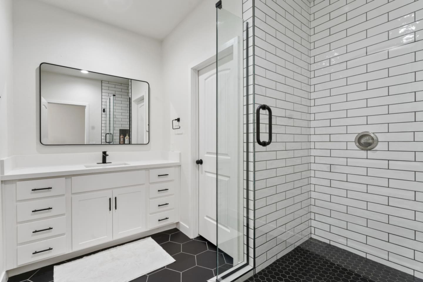 Primary bathroom with walk-in shower, subway tile, vanity storage, and a clean modern layout.