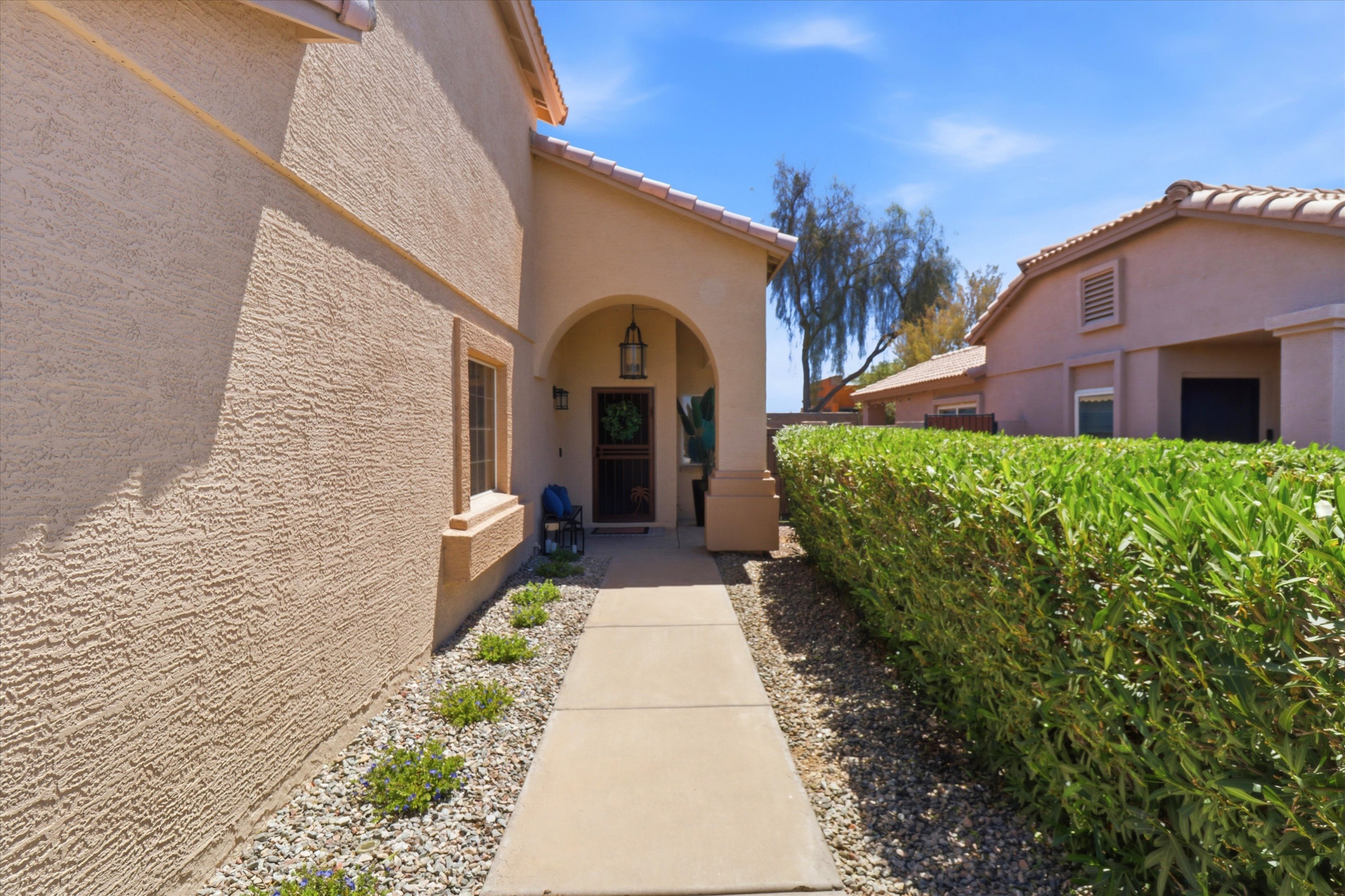 Covered entry with arched detail, bench seating, and a shaded arrival path to the home.