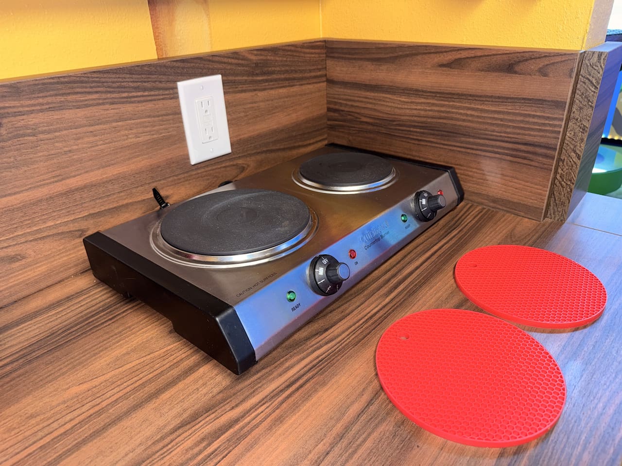 Ready-to-cook PORTABLE electric stovetop in the full compact kitchen at Mario's Mini Mansion, nearOrlando, FL! Smooth black cooktop, red silicone trivets, & wood counters provide everything you need for delicious family meals in this themed getaway.