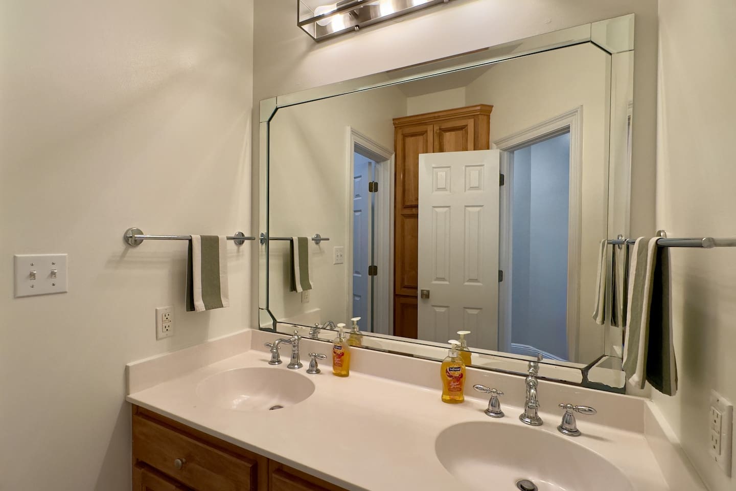 Chrome faucets, a large framed mirror, and a stylish light fixture create a fresh, contemporary look.