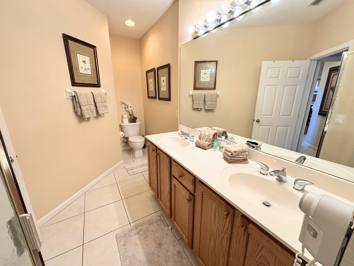 Spacious bathroom featuring a double-sink vanity, large mirror, tile flooring, and clean neutral finishes.
